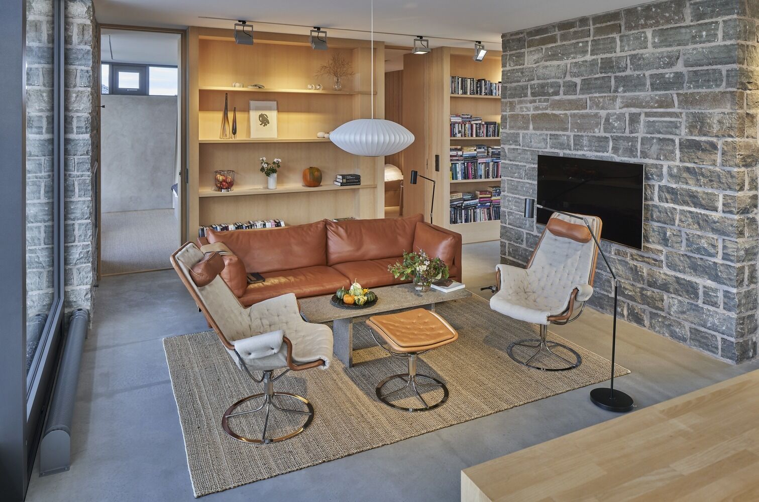 The same limestone used outside continues indoors, forming a central wall that separates the main living room from a smaller sitting area with a fireplace. This transition from exterior to interior feels seamless, with materials carrying through the entire home.