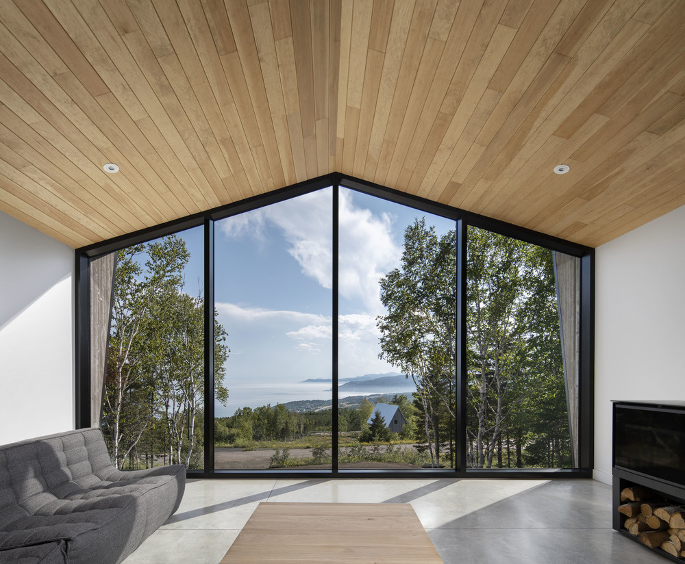 A large wall of windows at one end of the living room frames the river, filling the space with light and bringing the outdoors inside.