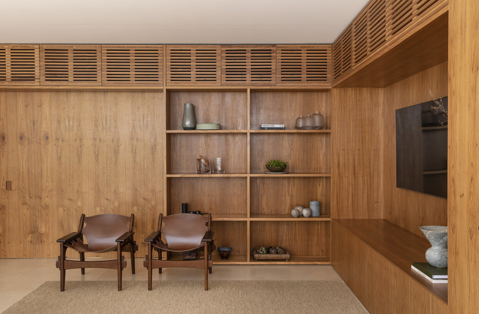 Glass walls and built-in freijó wood shelves connect living and dining areas with natural light and warmth.