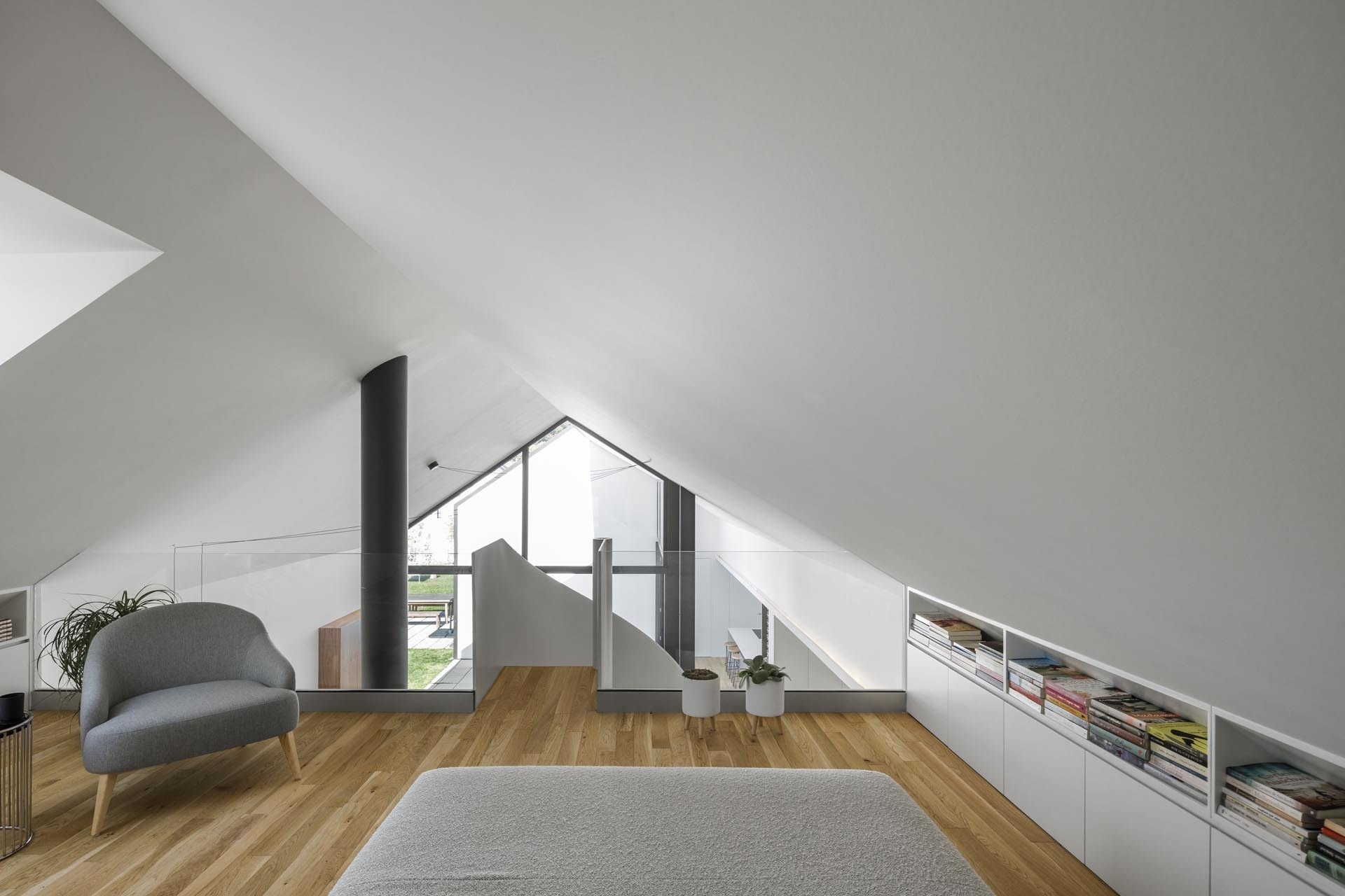 A white spiral staircase leads to a cozy loft beneath the gabled roof, offering a quiet space for reading and relaxation.