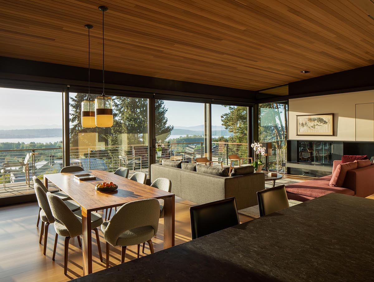 A dining space that opens to a balcony with wide views of water and mountains, blending indoor and outdoor living.