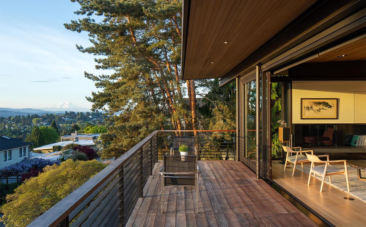 A dining space that opens to a balcony with wide views of water and mountains, blending indoor and outdoor living.