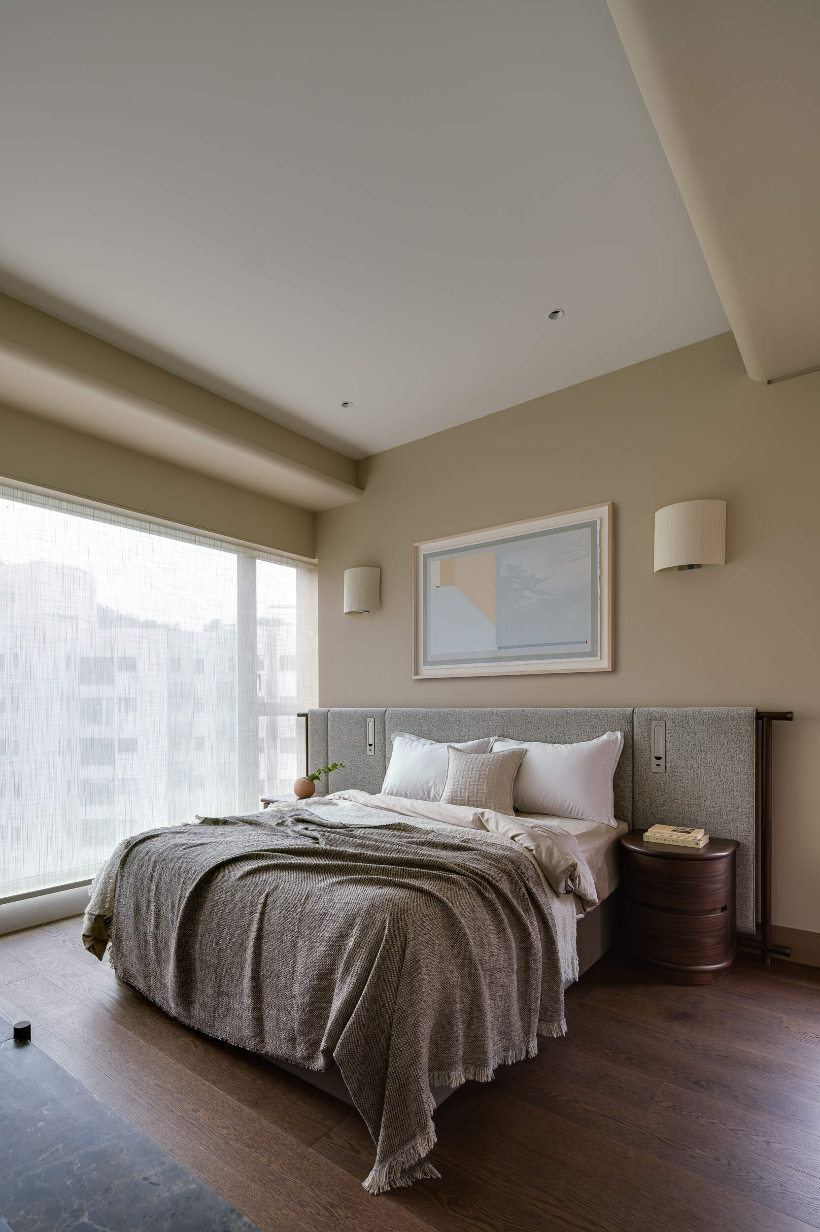 In the primary bedroom, soft textures, filtered light, and a custom fabric headboard create a calm, cocoon-like retreat.