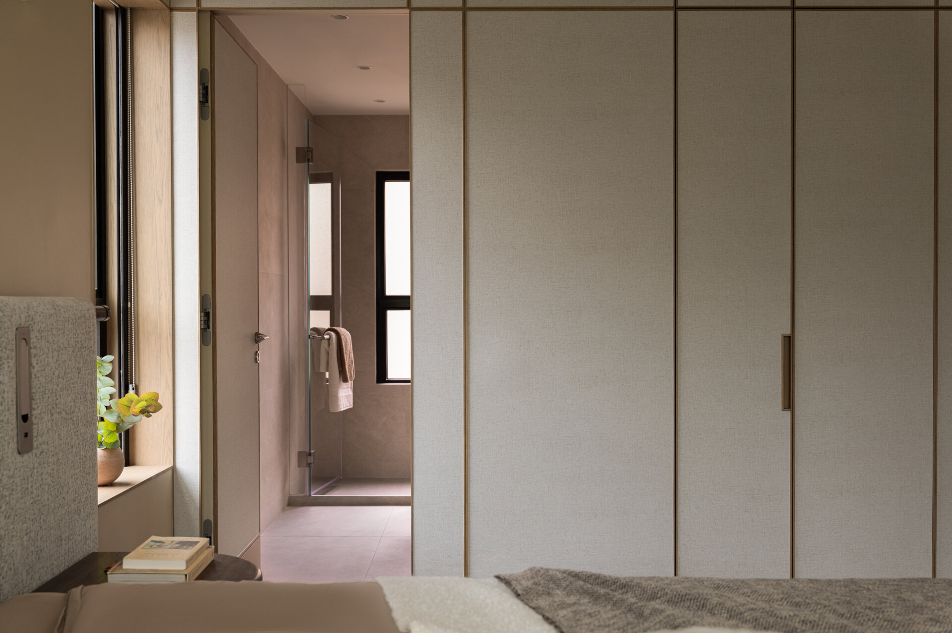 In the primary bedroom, soft textures, filtered light, and a custom fabric headboard create a calm, cocoon-like retreat.