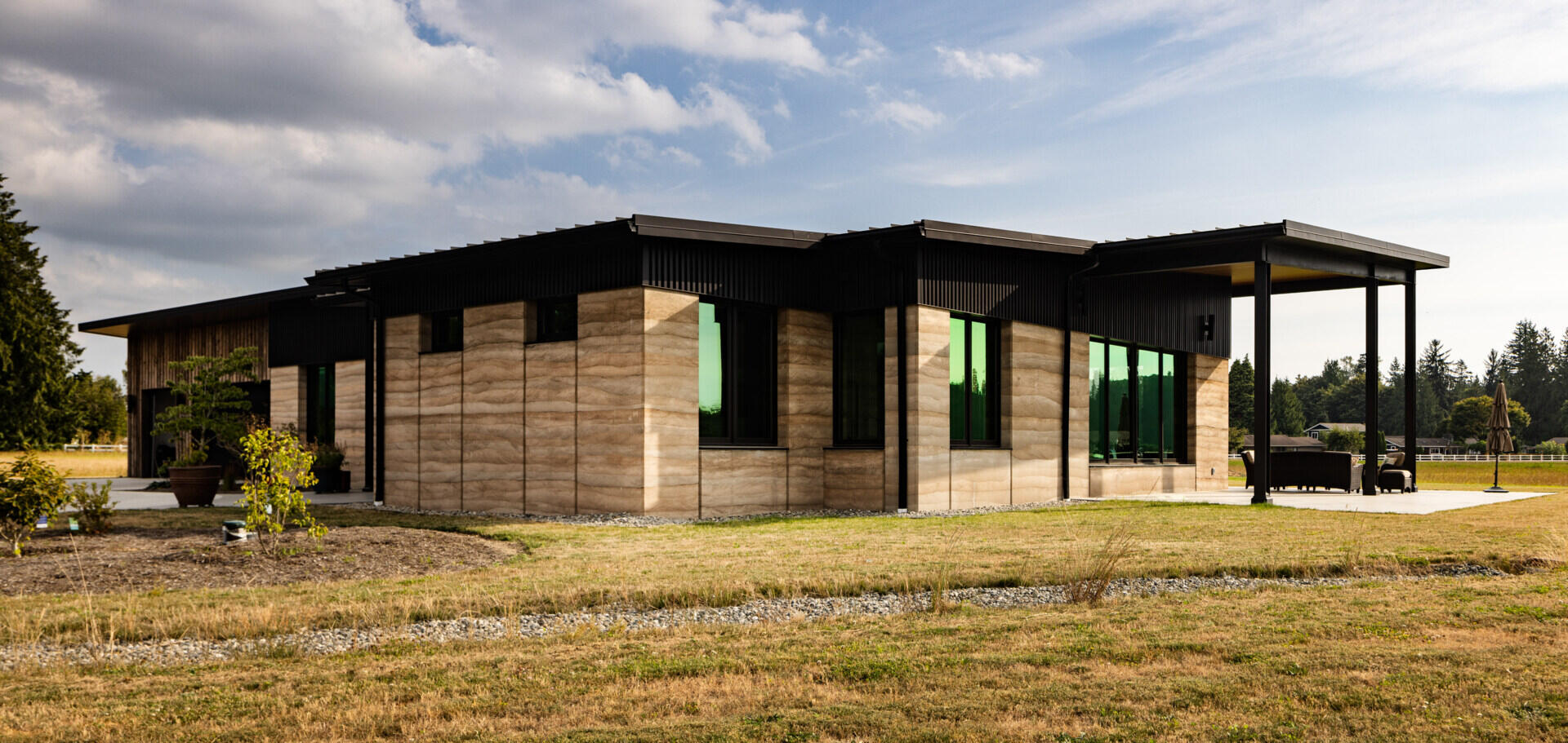 A rammed earth home in Washington’s Skagit Valley uses thick insulated walls, solar panels, and passive design to create an energy efficient house built for life beside farmland.