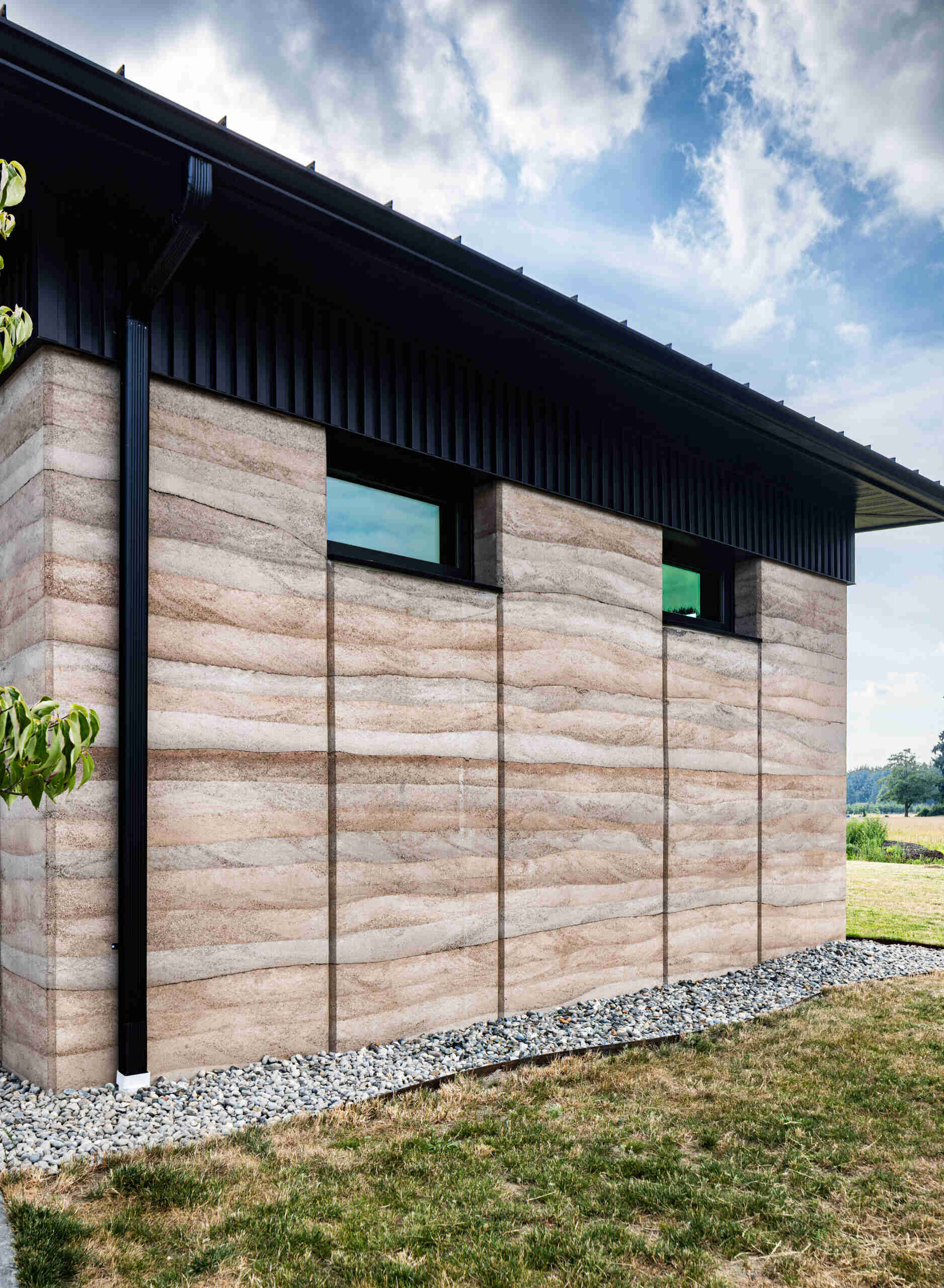 The home’s 24 inch thick walls combine two layers of rammed earth with a core of rigid insulation, creating a structural wall system that delivers durability and energy efficiency.
