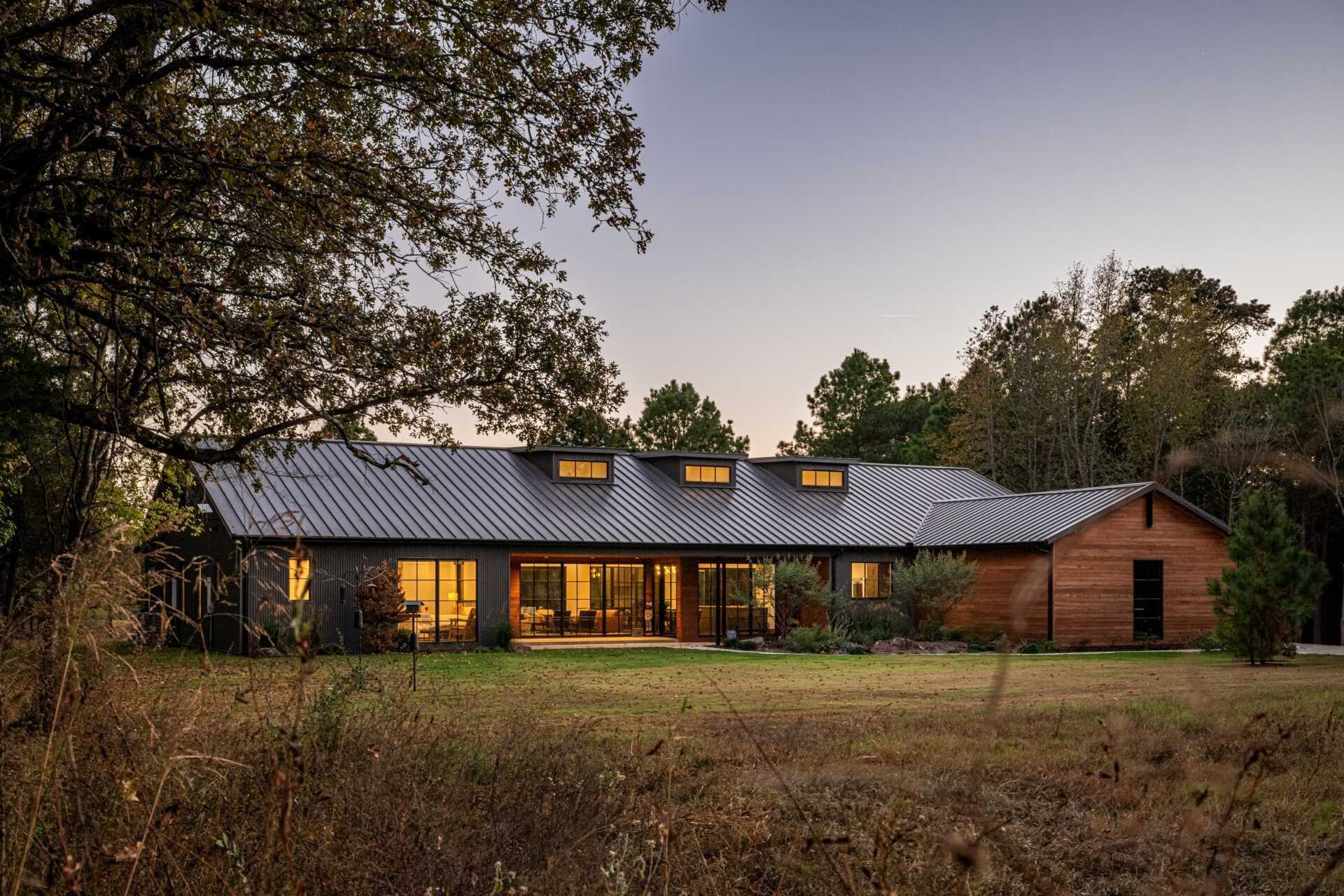 The restrained material palette of wood and metal combines rustic textures with refined modern finishes, integrating this ranch house into its East Texas context without competing with the landscape.