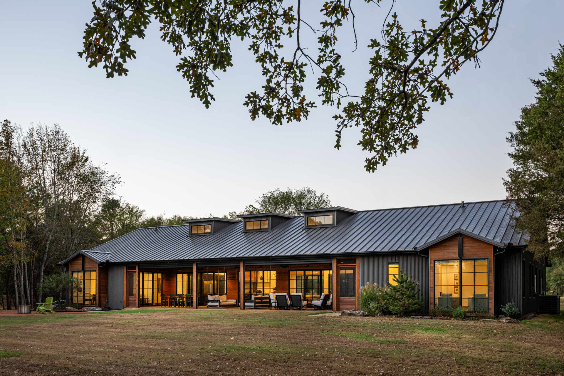The patio extends the interiors. Fixed screen doors allow access when larger insect screens are deployed. The porch, furnished with a variety of seating area, is carefully proportioned to maximize light, ventilation, and visual connection to the pond and tree canopy, supporting both casual and formal gatherings.