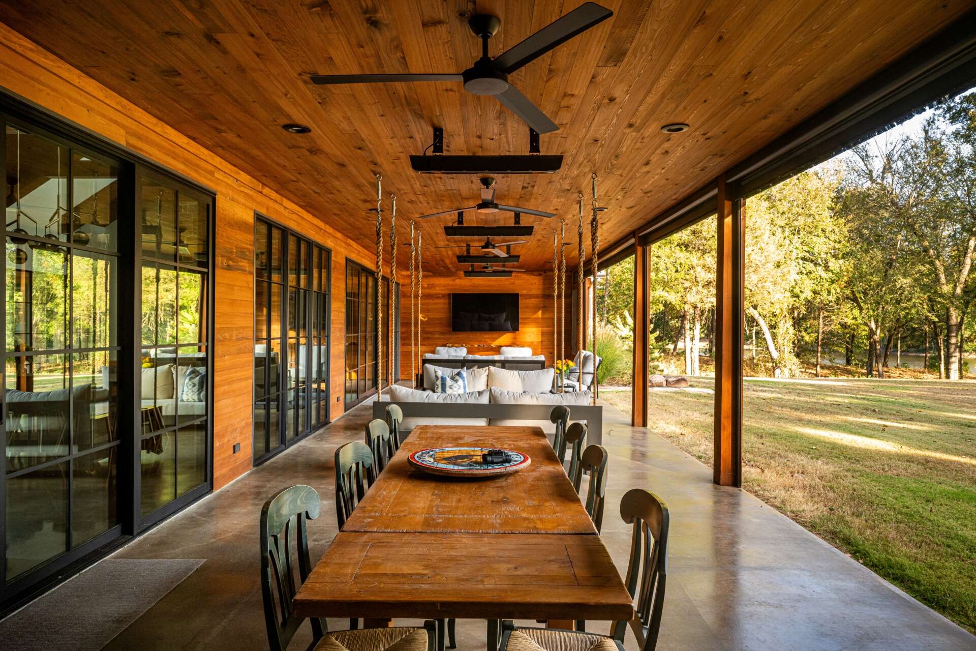 The patio extends the interiors. Fixed screen doors allow access when larger insect screens are deployed. The porch, furnished with a variety of seating area, is carefully proportioned to maximize light, ventilation, and visual connection to the pond and tree canopy, supporting both casual and formal gatherings.