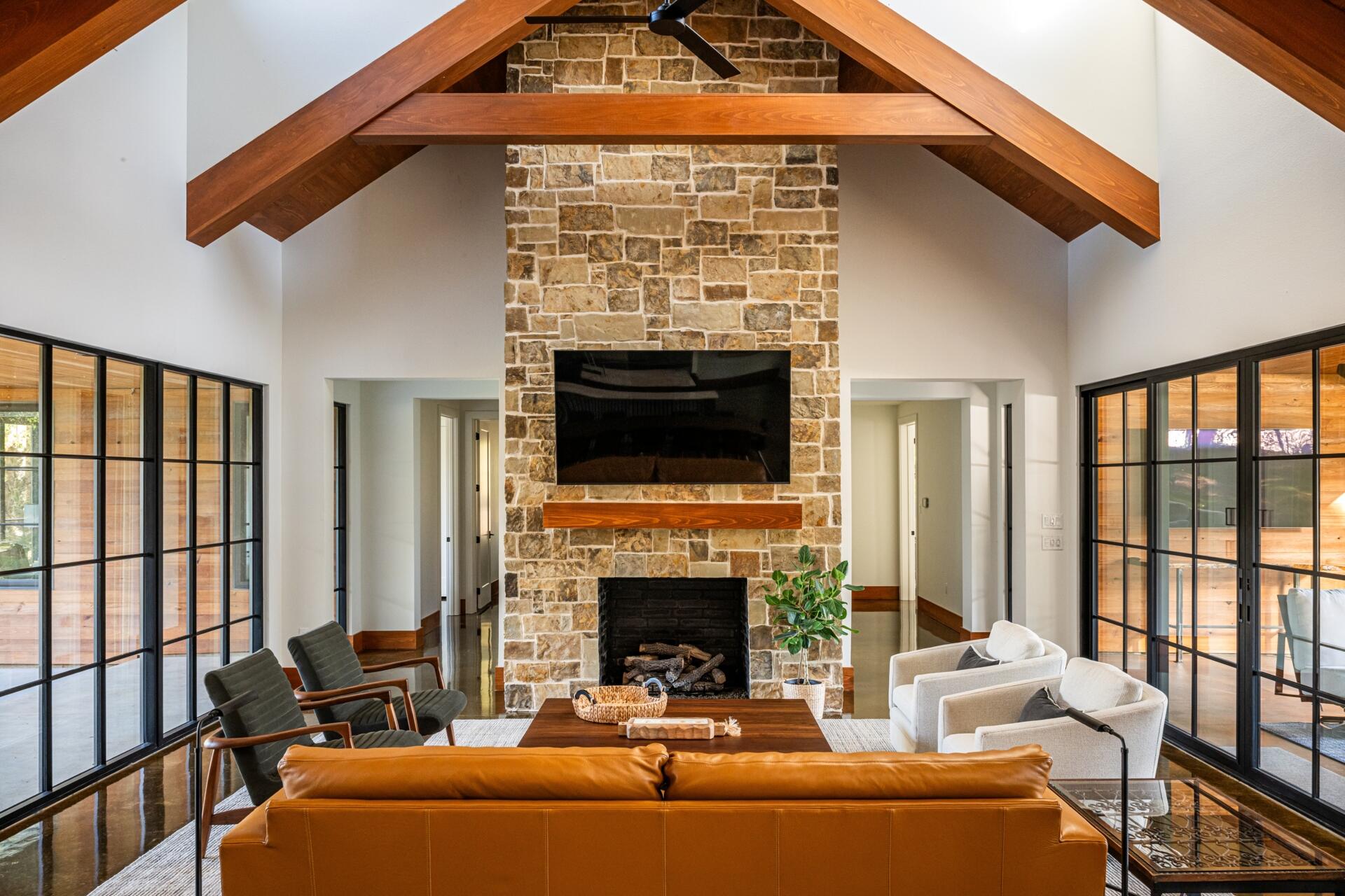 A central great room with a stone fireplace surround, accommodates dining, socializing, and circulation.