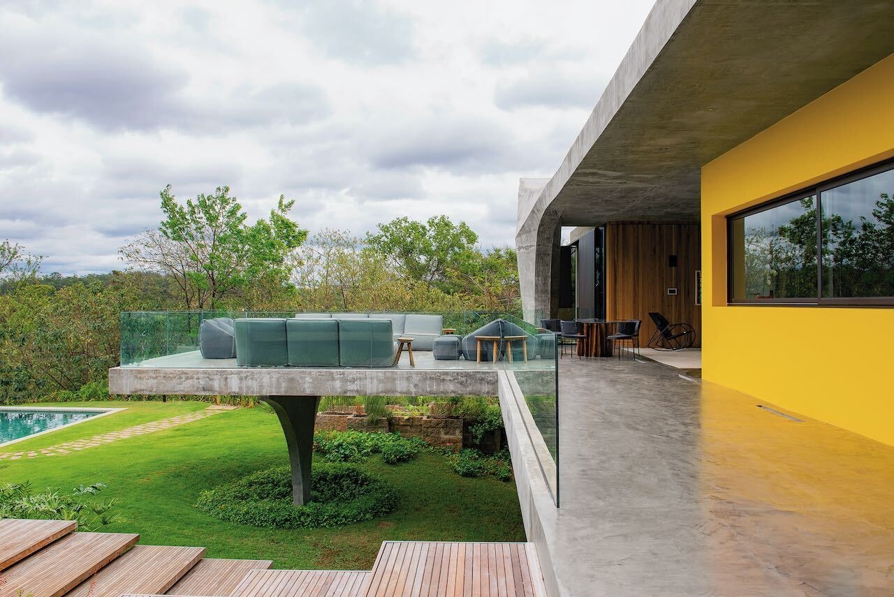 An expansive concrete balcony with wood stairs leading to outdoor spaces, extending the home across multiple levels.