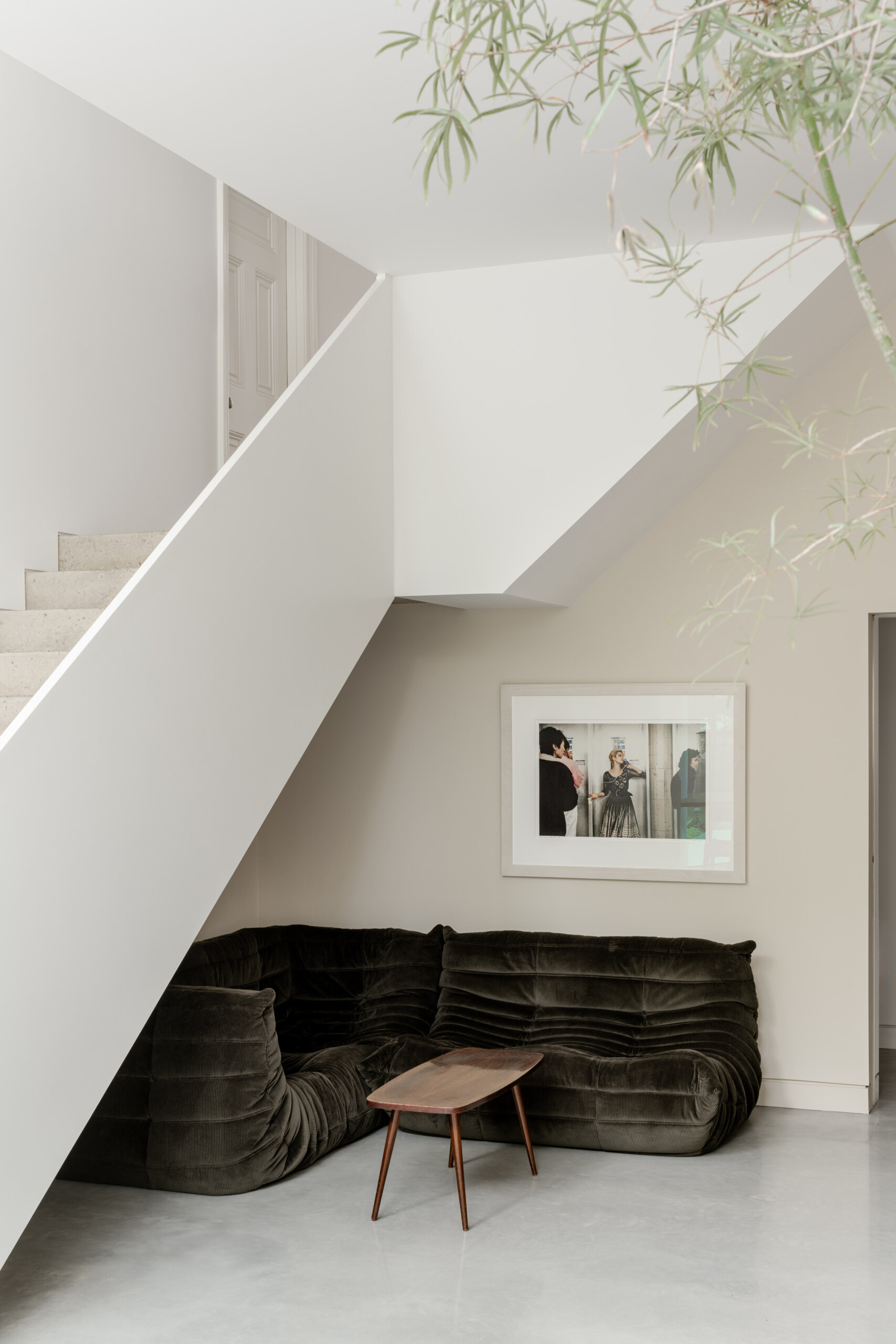 The sitting area under the stairs creates a tucked-away corner within the layered layout of the home, offering a quieter space that remains connected to the main living areas.
