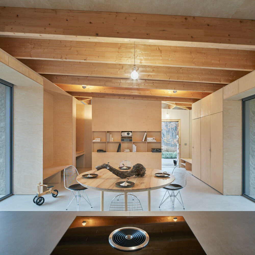 An open-plan cabin interior with warm wood finishes and a bold stainless steel kitchen as the focal point.