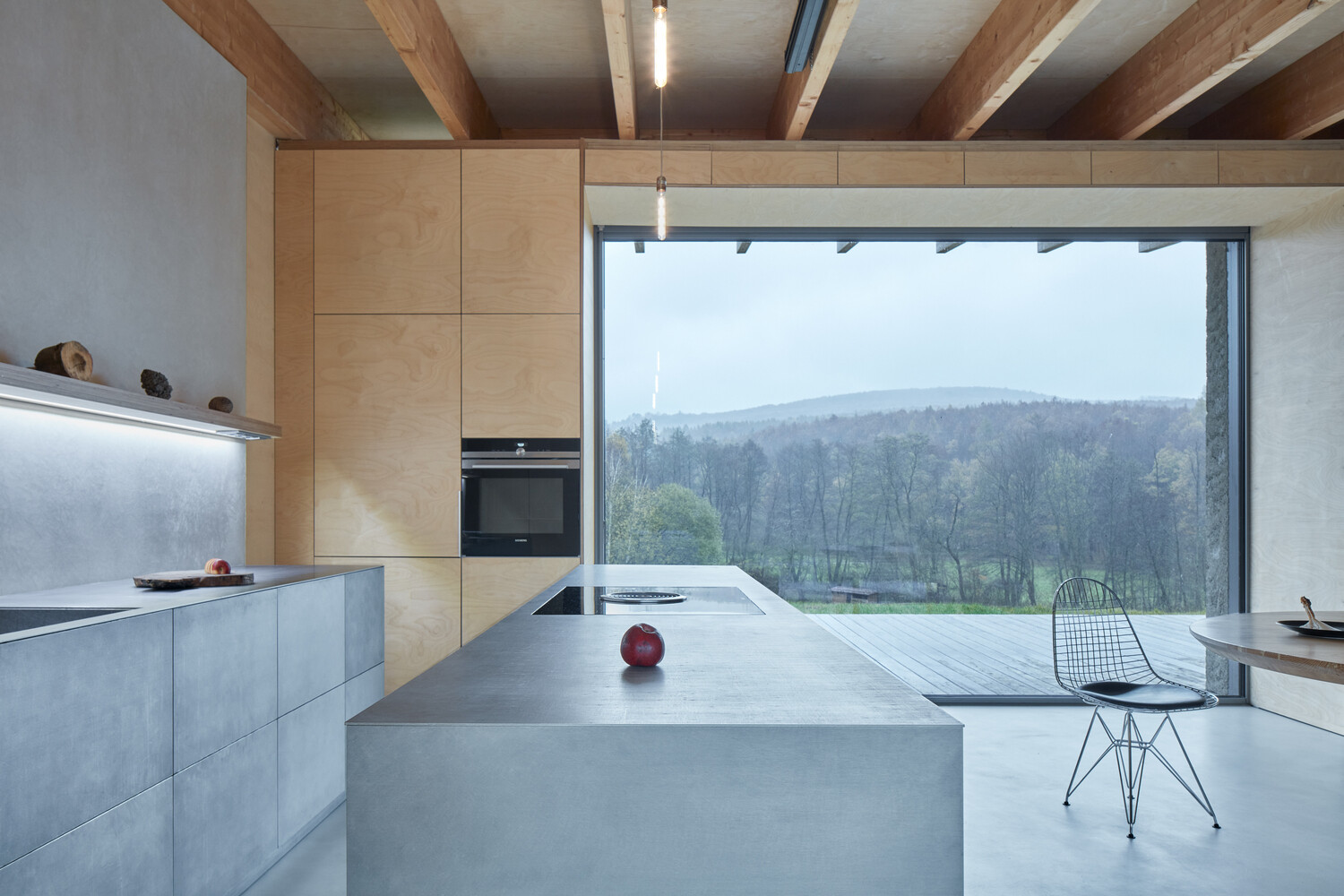 An open-plan cabin interior with warm wood finishes and a bold stainless steel kitchen as the focal point.