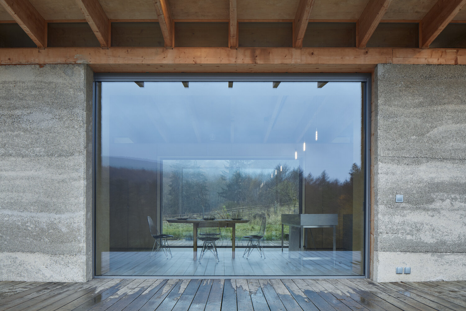 Floor-to-ceiling glass doors open a modern cabin to the forest, filling the interior with light and views.