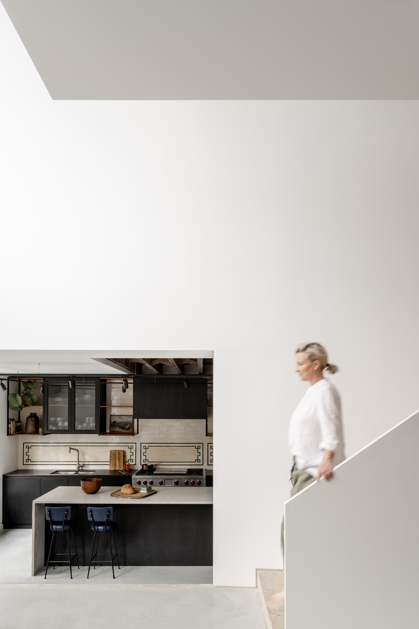 The main staircase is constructed from concrete using reclaimed aggregate from demolition waste, connecting the home’s tiered layout while supporting the project’s sustainability goals.