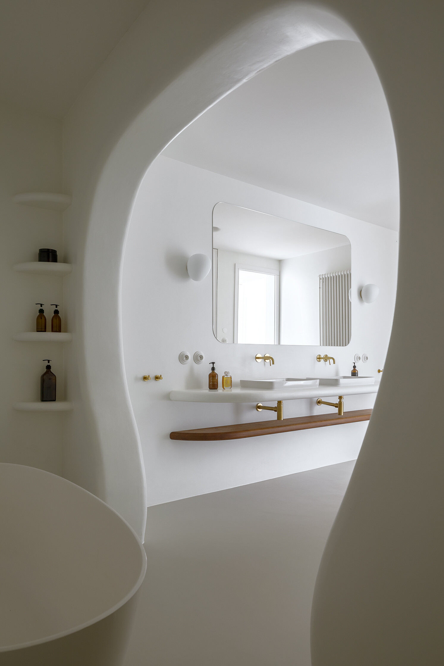 A family bathroom with a bathtub and shower alcove, designed as sculptural niches that add depth and softness.