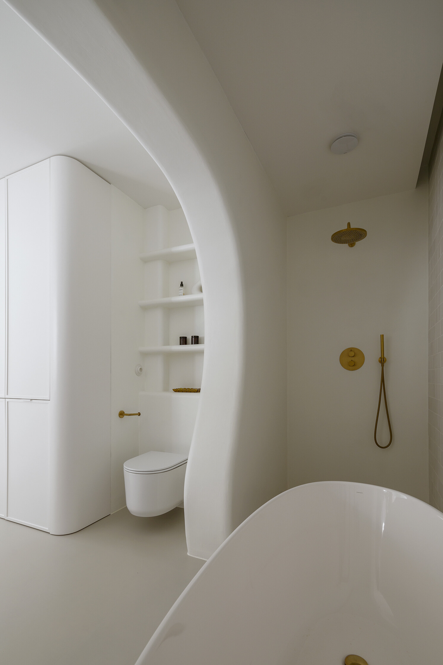A family bathroom with a bathtub and shower alcove, designed as sculptural niches that add depth and softness.