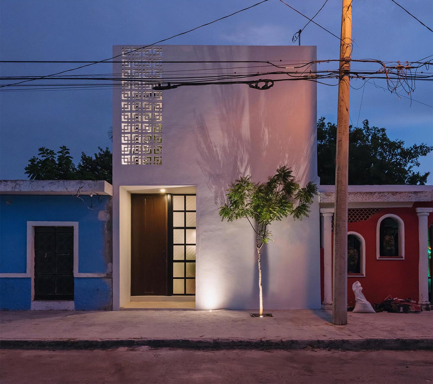 A compact modern home that reveals far more than its calm white exterior suggests. From the street, the house presents a restrained presence, but stepping inside reveals a layered sequence of spaces filled with greenery, light, and carefully framed views.