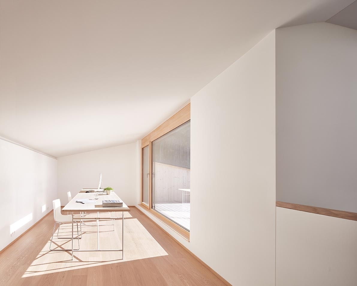 White walls and natural wood accents meet beside a large window that fills the room with soft daylight.