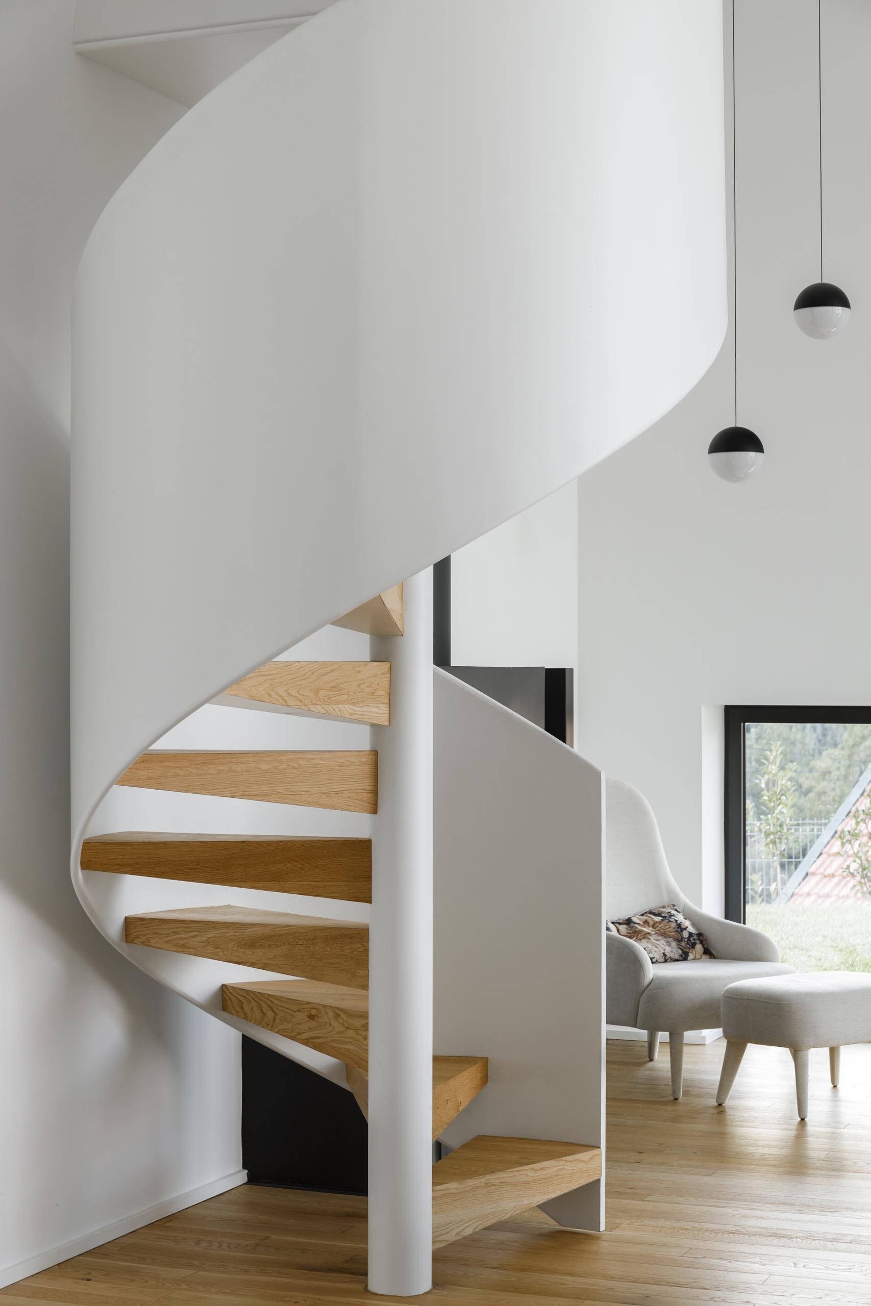 A white spiral staircase leads to a cozy loft beneath the gabled roof, offering a quiet space for reading and relaxation.