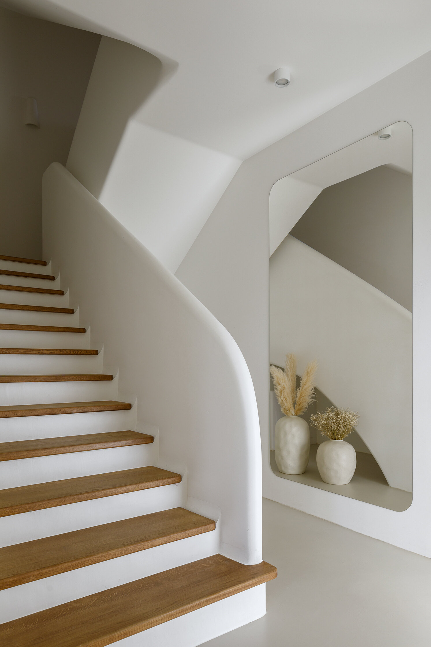 A sculptural staircase with wood treads and a flowing silhouette that anchors the home while connecting each space.