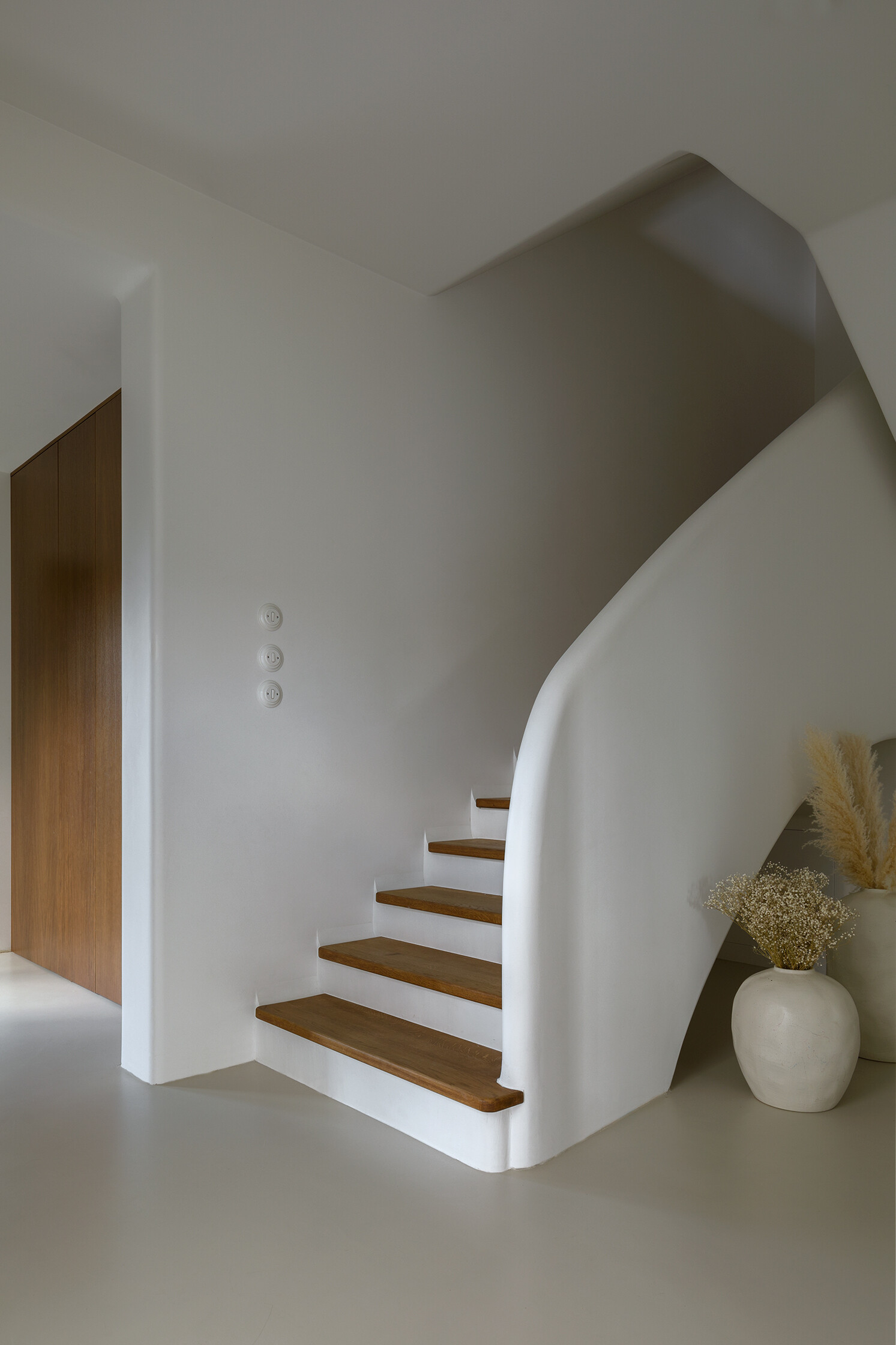 A sculptural staircase with wood treads and a flowing silhouette that anchors the home while connecting each space.