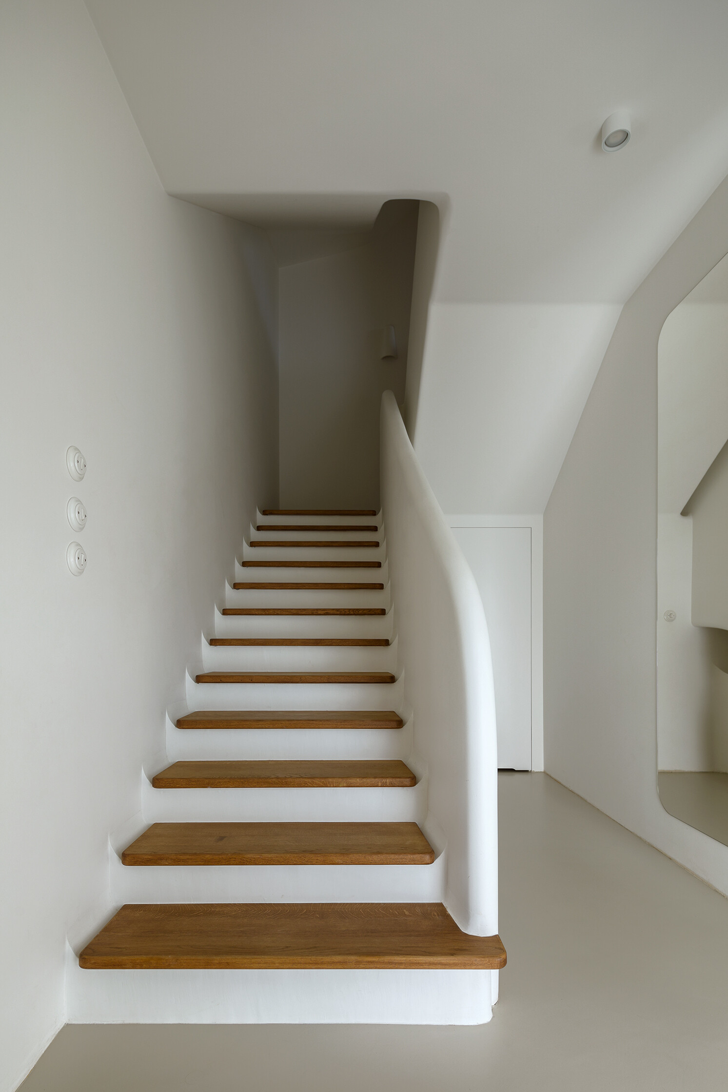 A sculptural staircase with wood treads and a flowing silhouette that anchors the home while connecting each space.