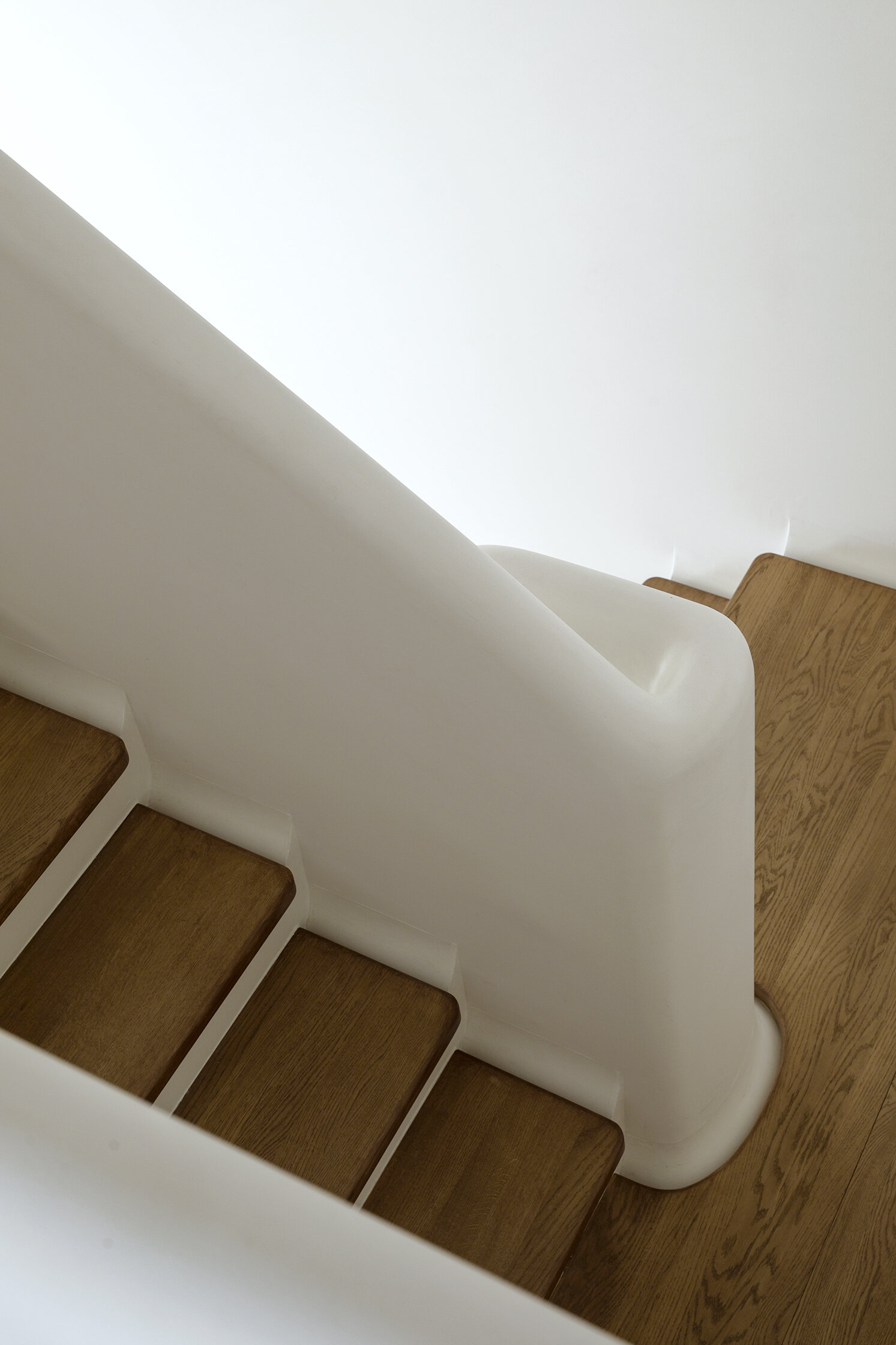 A sculptural staircase with wood treads and a flowing silhouette that anchors the home while connecting each space.