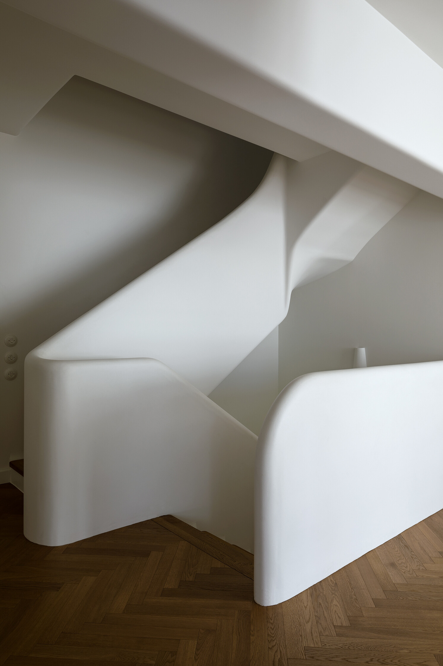 A sculptural staircase with wood treads and a flowing silhouette that anchors the home while connecting each space.