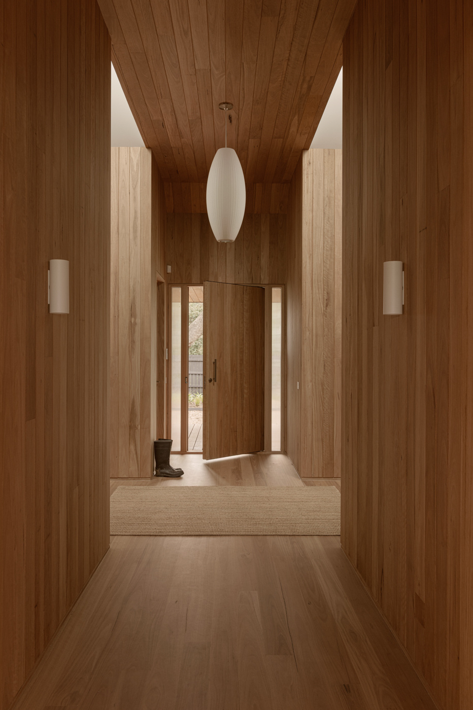 A timber-lined entry hall with skylights leads into a narrow linkway between the two pavilions, creating a sequence of shifting spaces throughout the house.