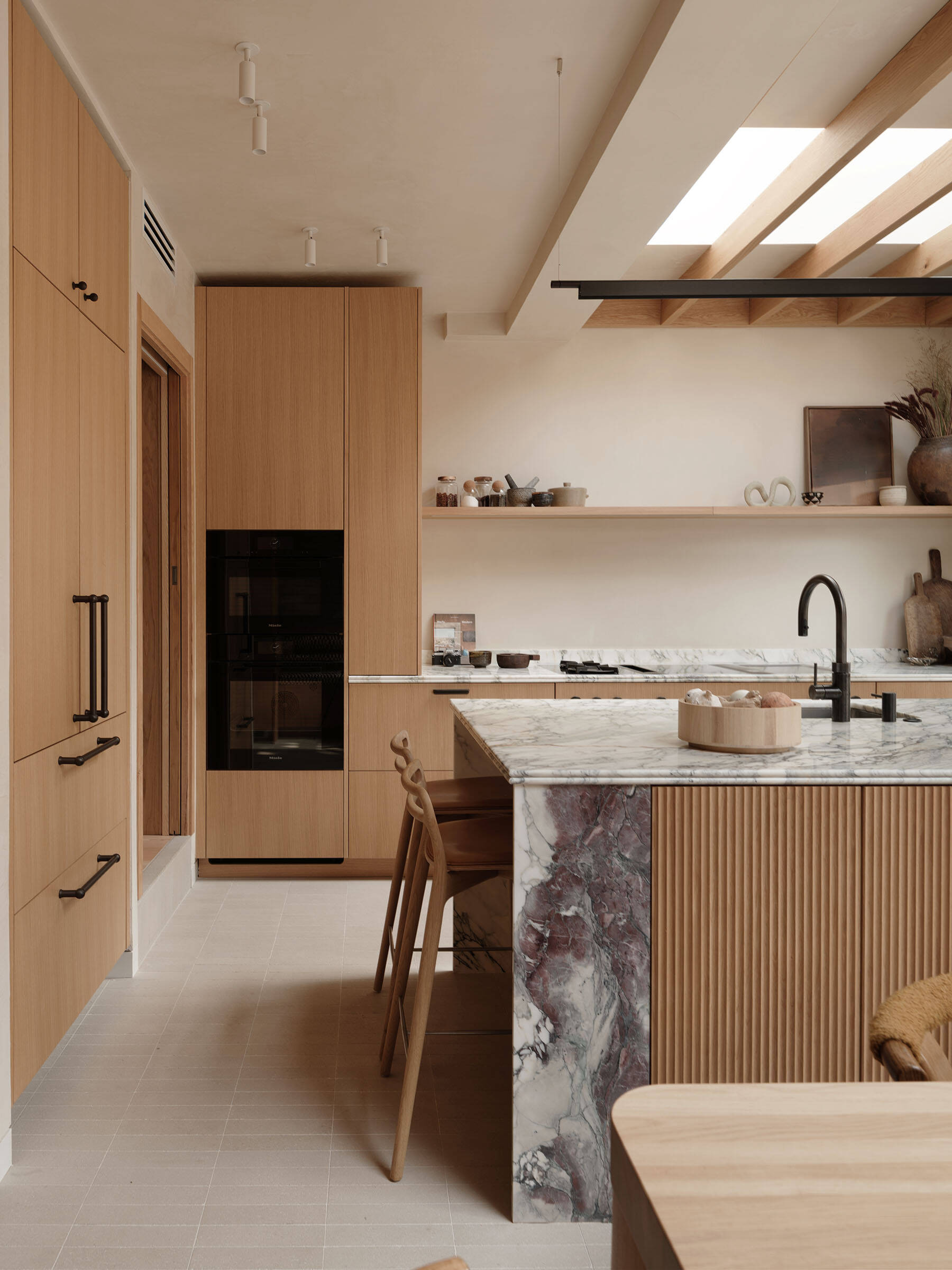 The kitchen is fully integrated into the overall layout rather than treated as a separate room. A consistent material palette of timber, stone, and plaster ensures visual continuity. This approach allows the kitchen to support both everyday routines and social use without feeling disconnected from the rest of the home.