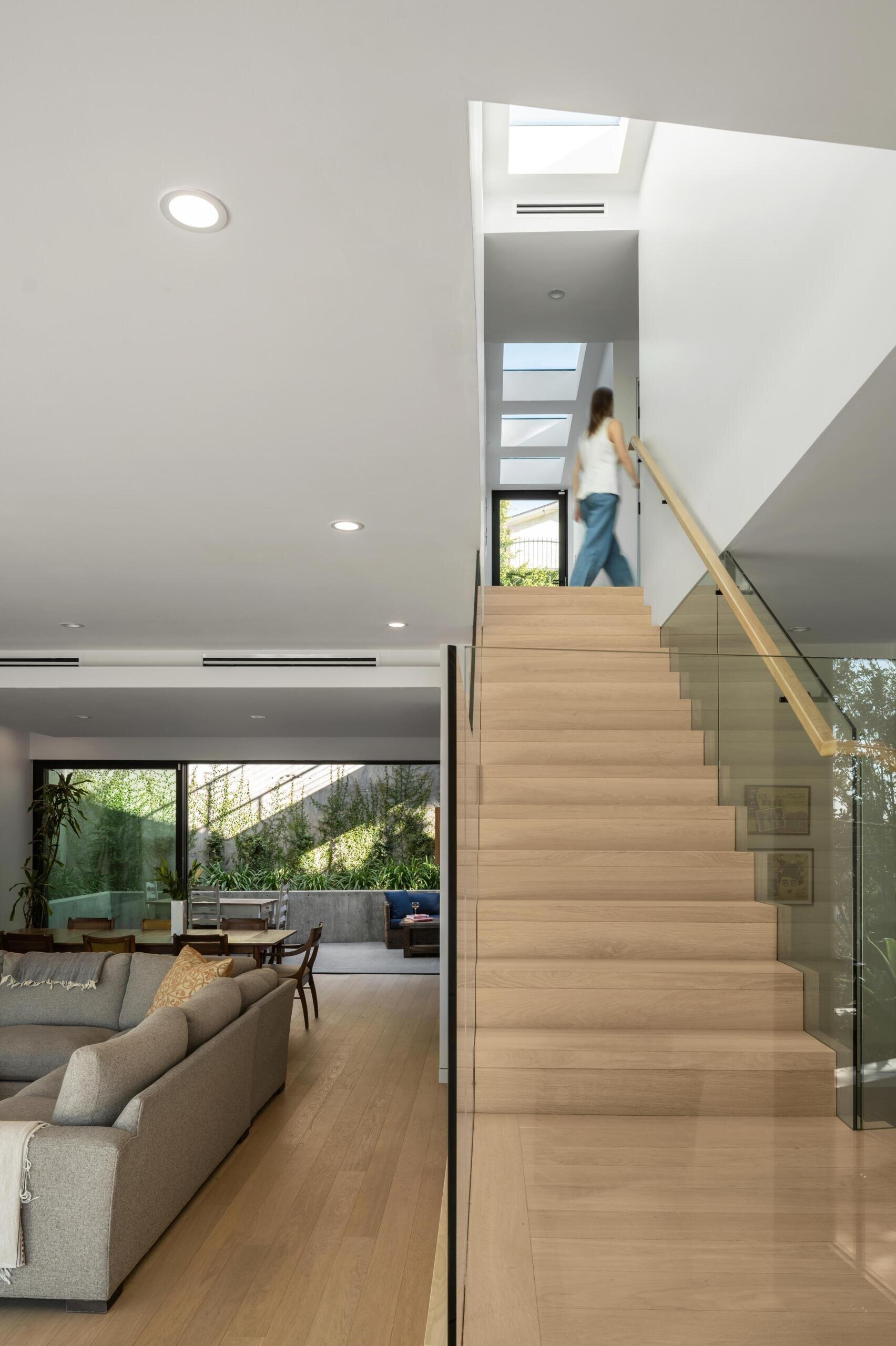 A central wood staircase ties the home together vertically. Running beneath a skylight, it brings light into the core of the house. As you move up or down, the changing light adds to the experience.