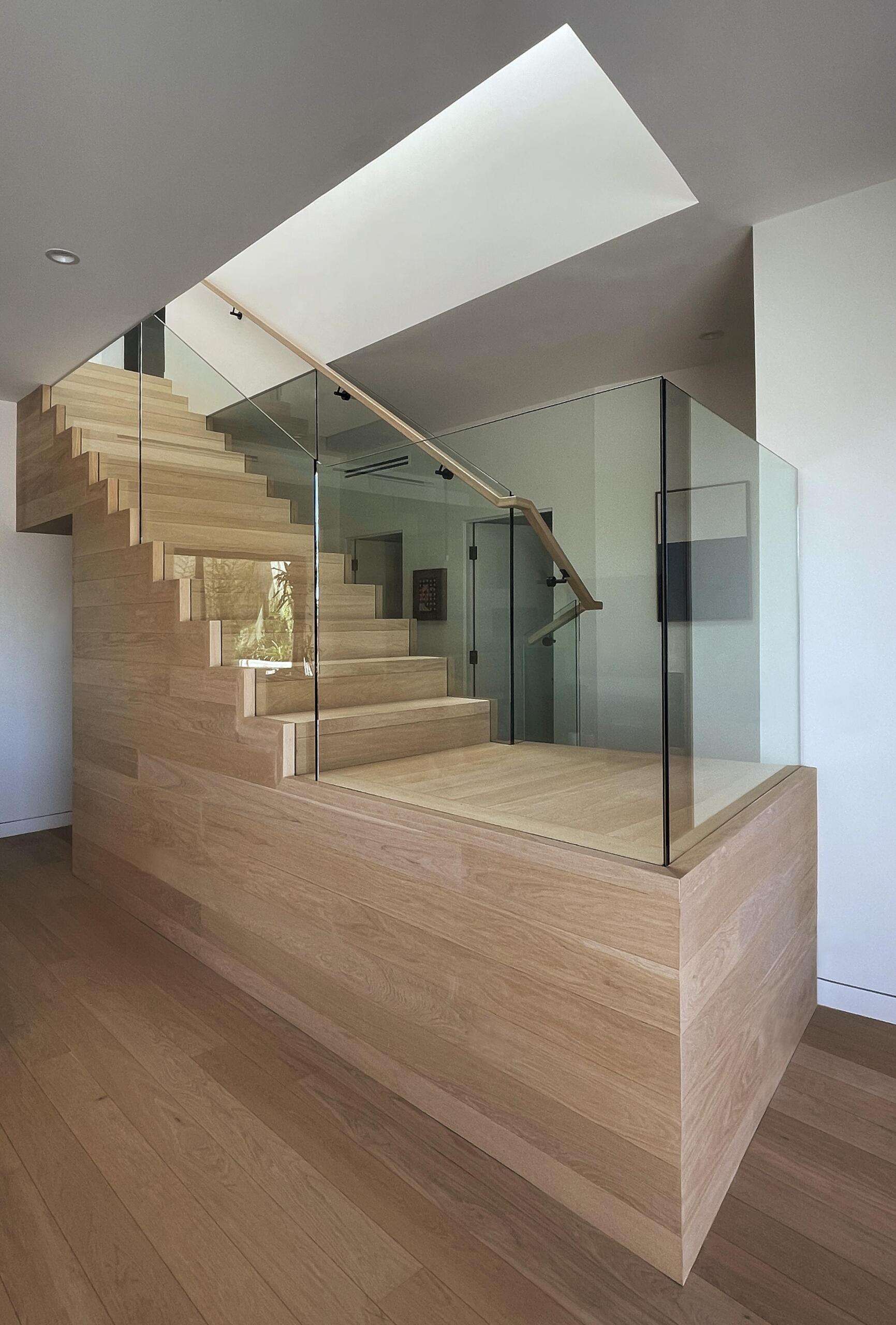 A central wood staircase ties the home together vertically. Running beneath a skylight, it brings light into the core of the house. As you move up or down, the changing light adds to the experience.