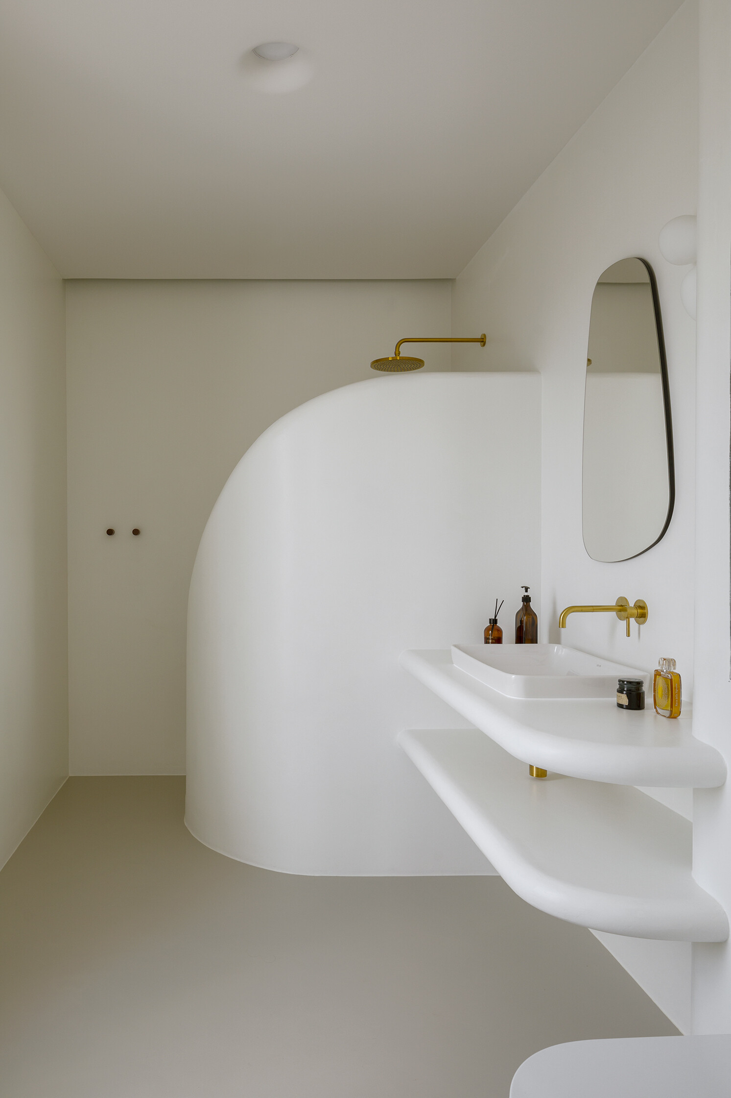 A spa-like ensuite with a curved walk-in shower and seamless surfaces that soften light and space.