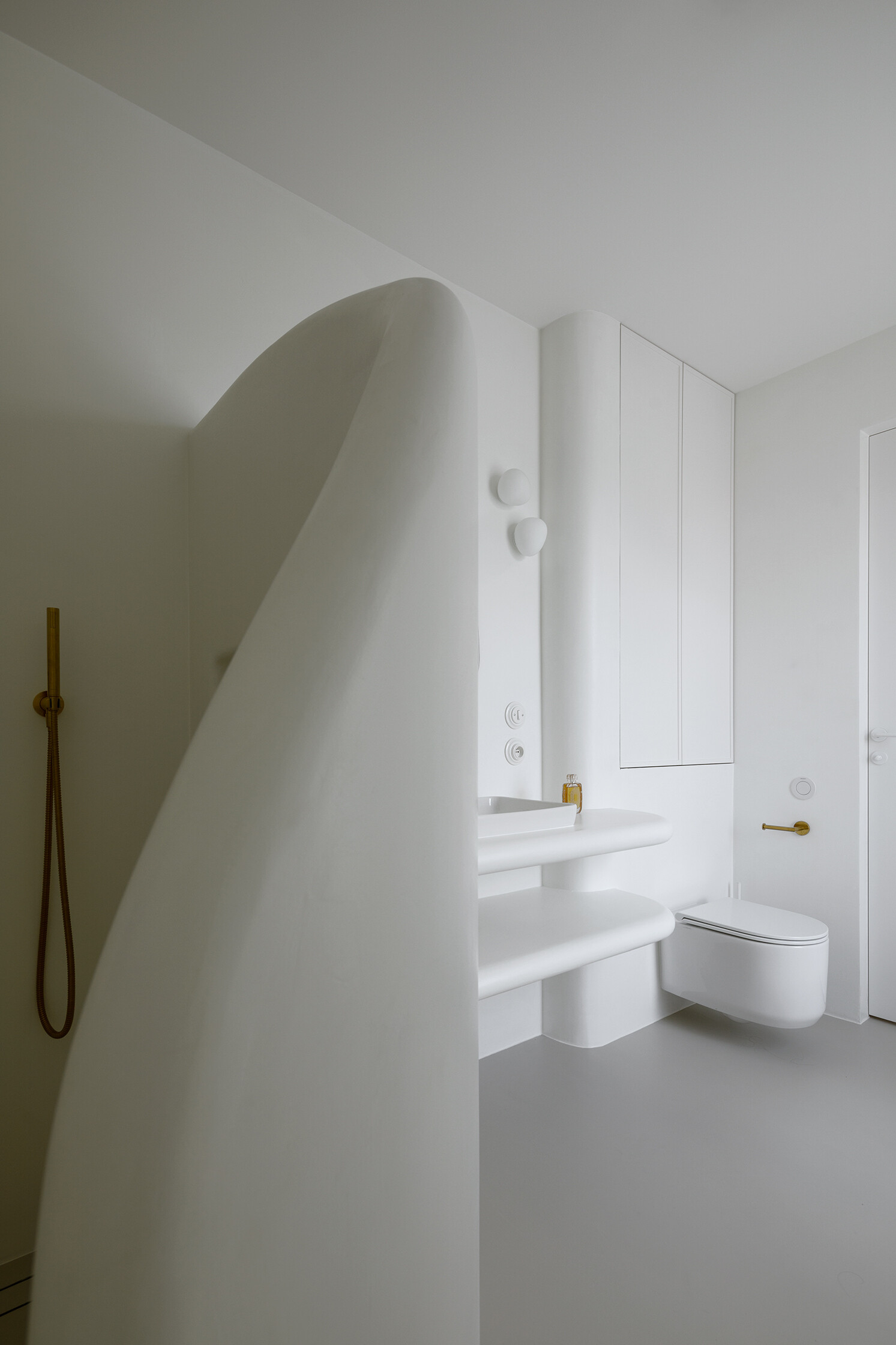 A spa-like ensuite with a curved walk-in shower and seamless surfaces that soften light and space.