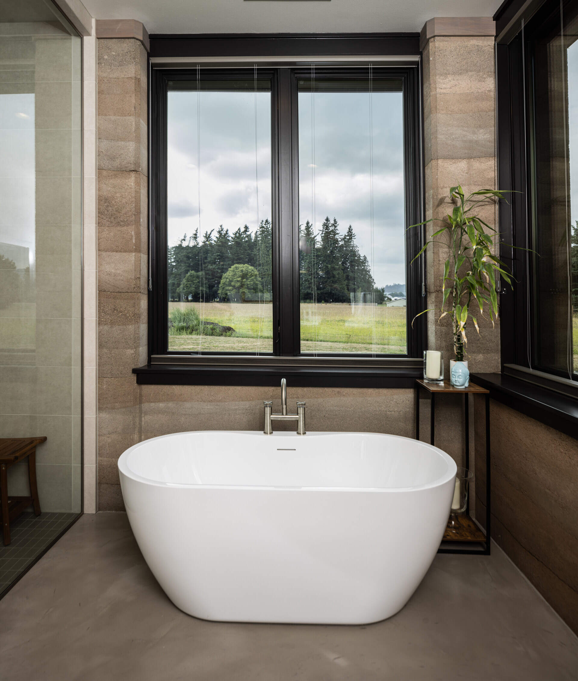 In the bathroom, a glass enclosed shower is adjacent to a freestanding bathtub that's positioned for views of the landscape.