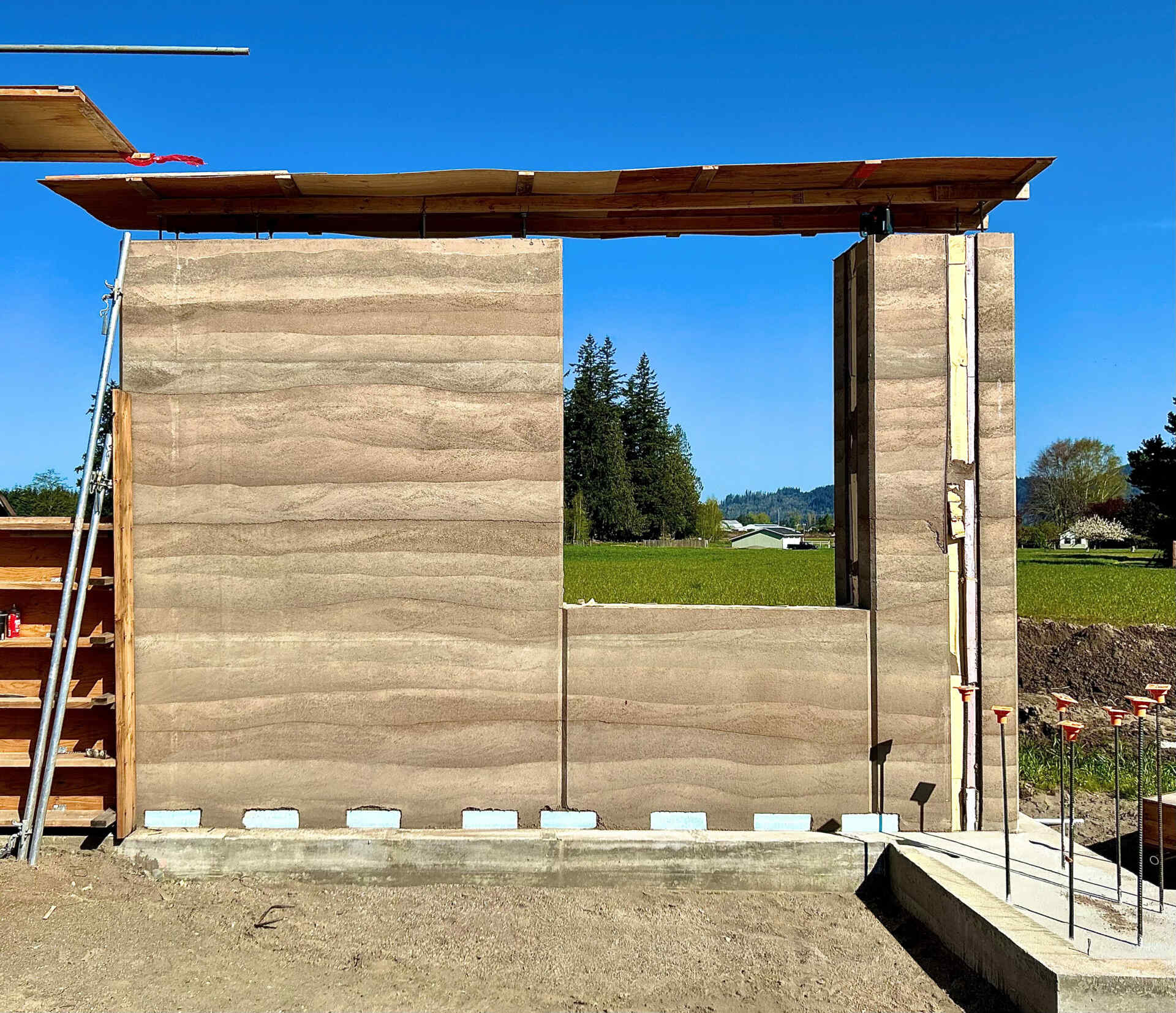 The rammed earth walls were formed by compacting layers of local soil, sand, and gravel inside specialized formwork, creating the distinctive horizontal bands seen throughout the house.