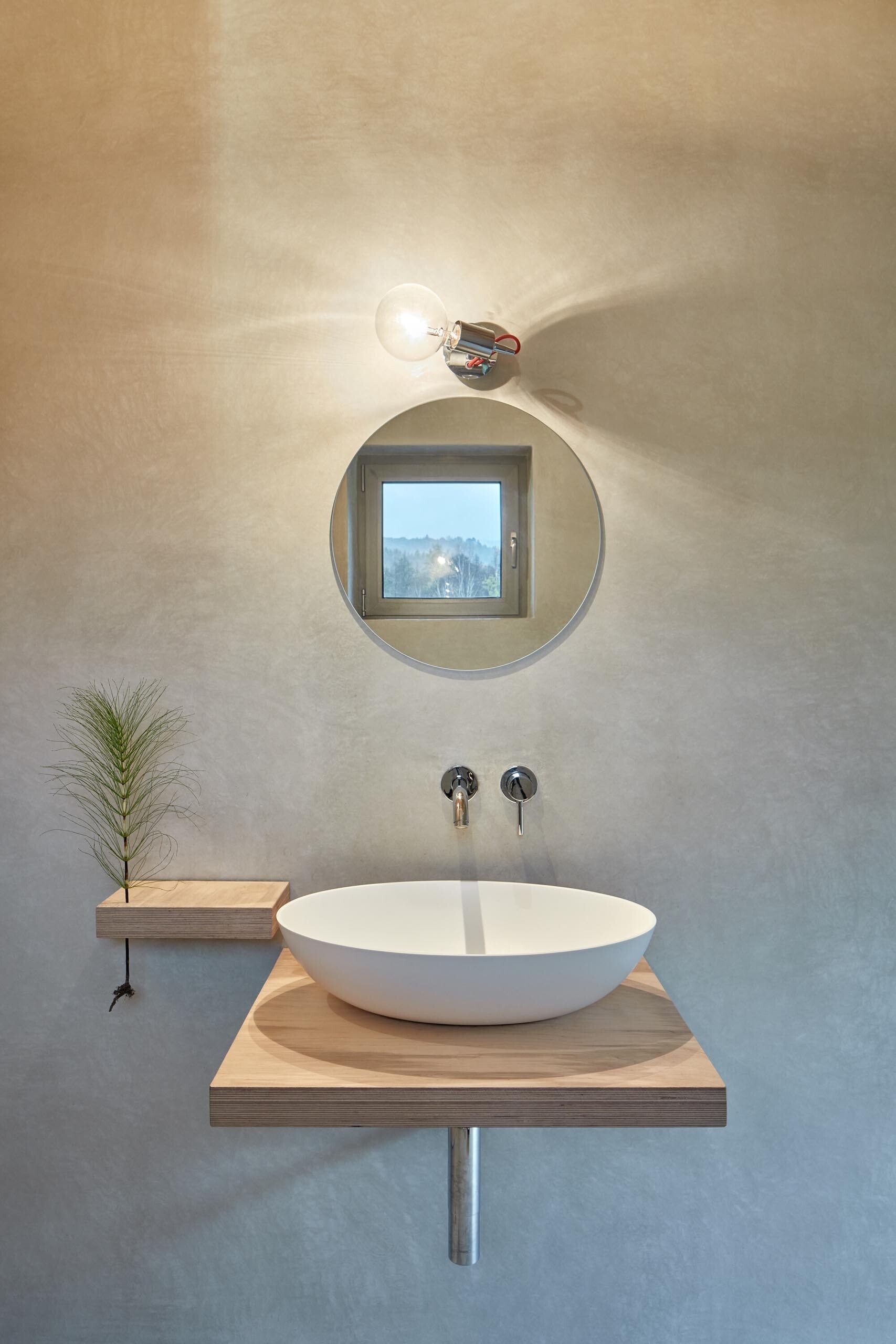 A bathroom with a sunken tub and large picture window, bringing natural light and forest views inside.