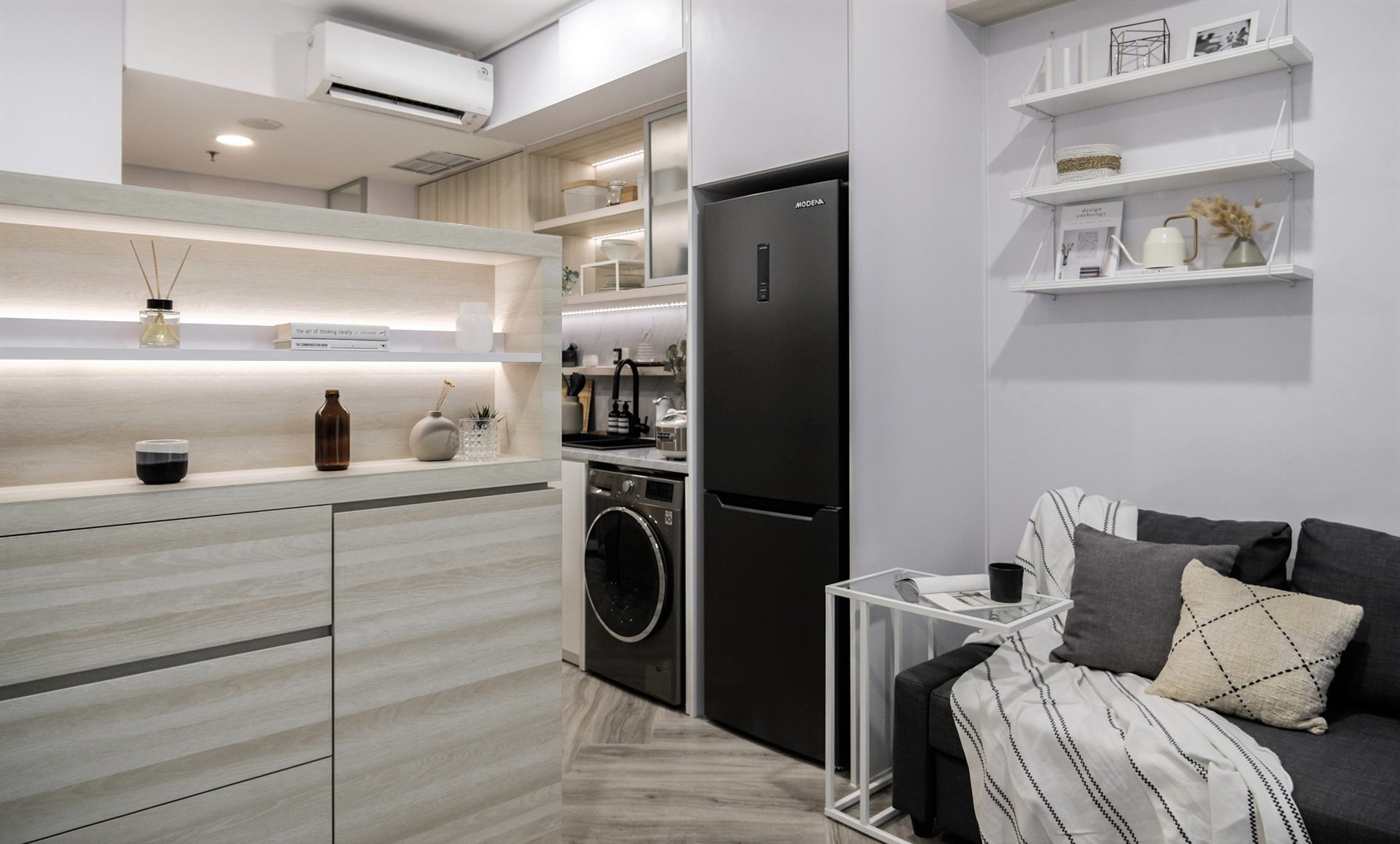 A sleek small kitchen with light wood cabinets and LED lighting, designed to keep a compact apartment feeling bright and uncluttered.