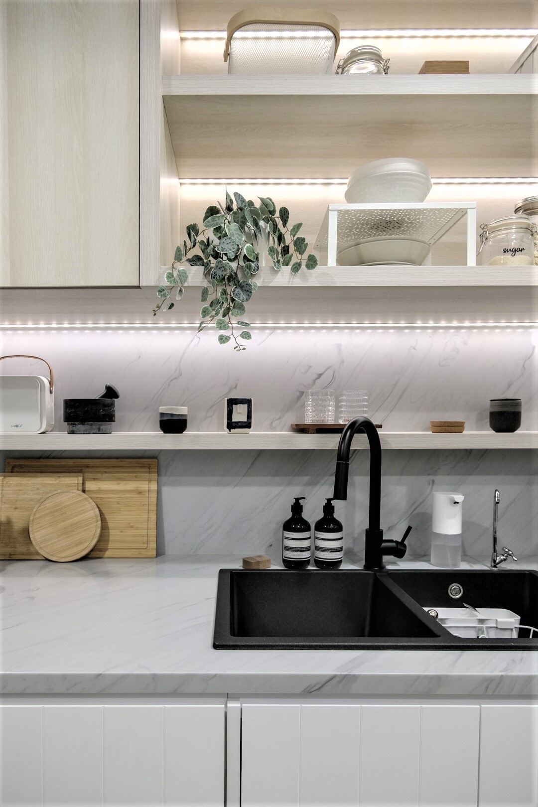 A sleek small kitchen with light wood cabinets and LED lighting, designed to keep a compact apartment feeling bright and uncluttered.