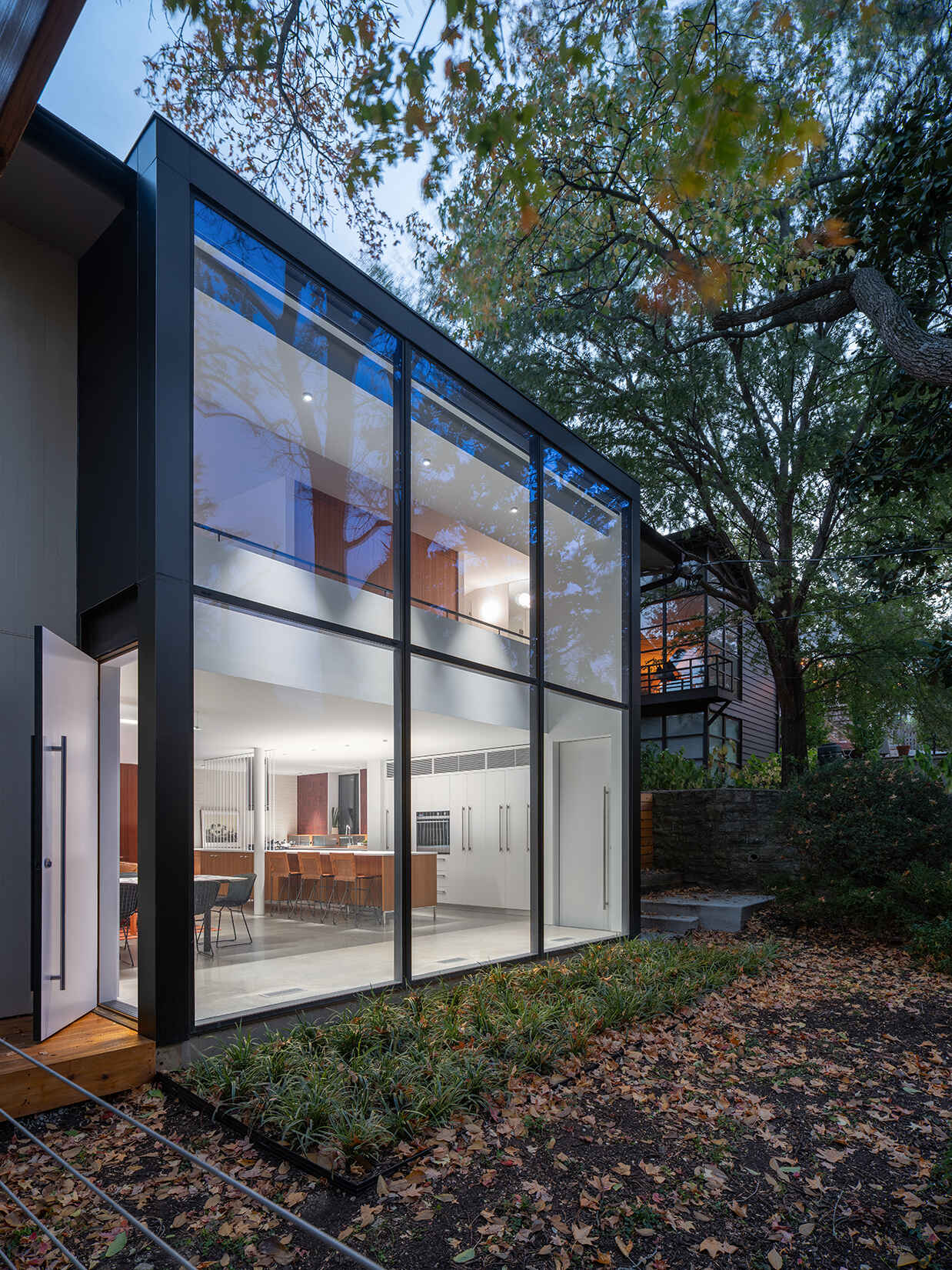 Along the rear wall, expansive glass and doors frame views of the wooded yard and draw natural light deep into the home.