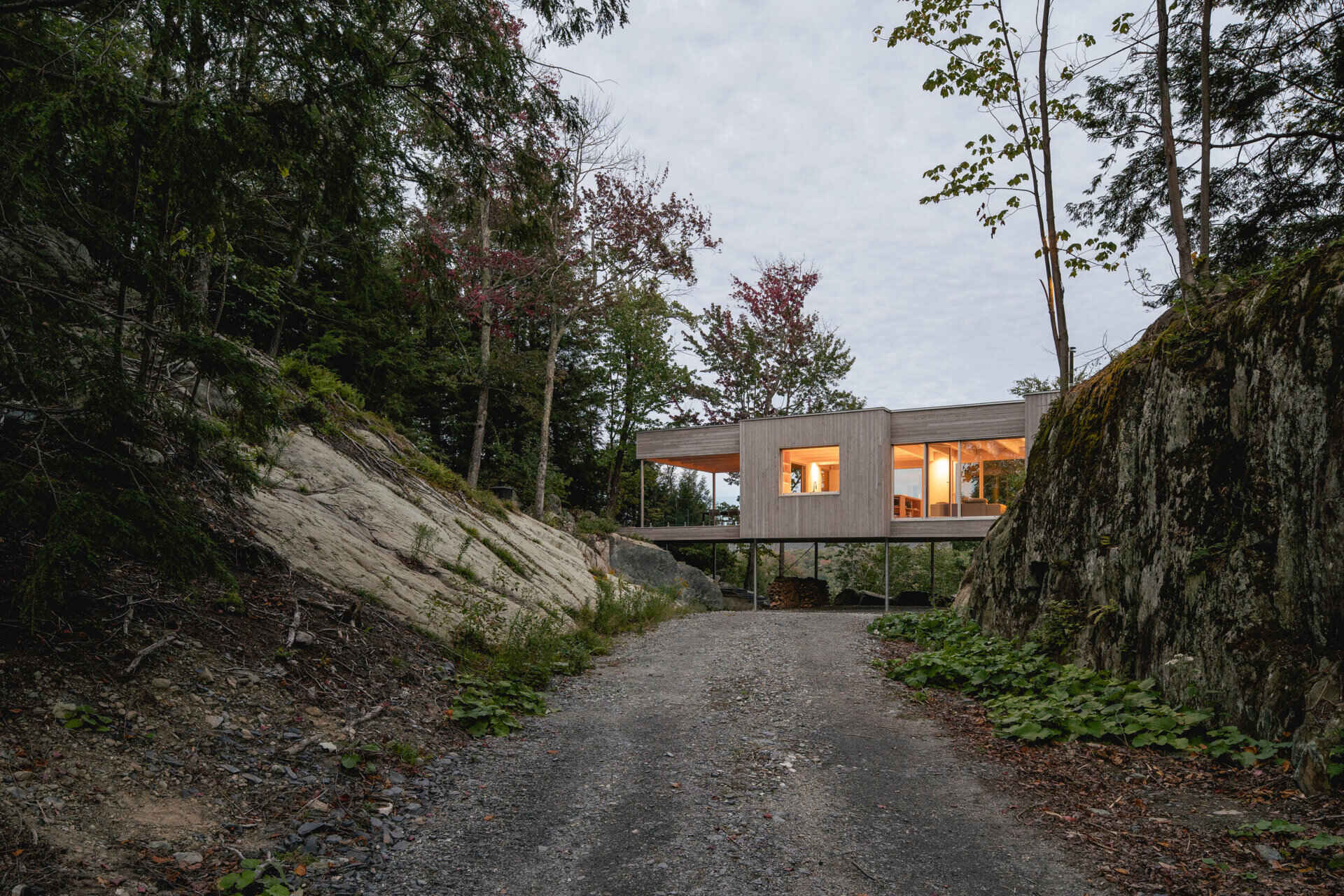 El revestimiento de cedro desgastado ayuda a que esta casa en el bosque se mezcle con el paisaje circundante, mientras que su estructura elevada sigue las formaciones rocosas naturales.