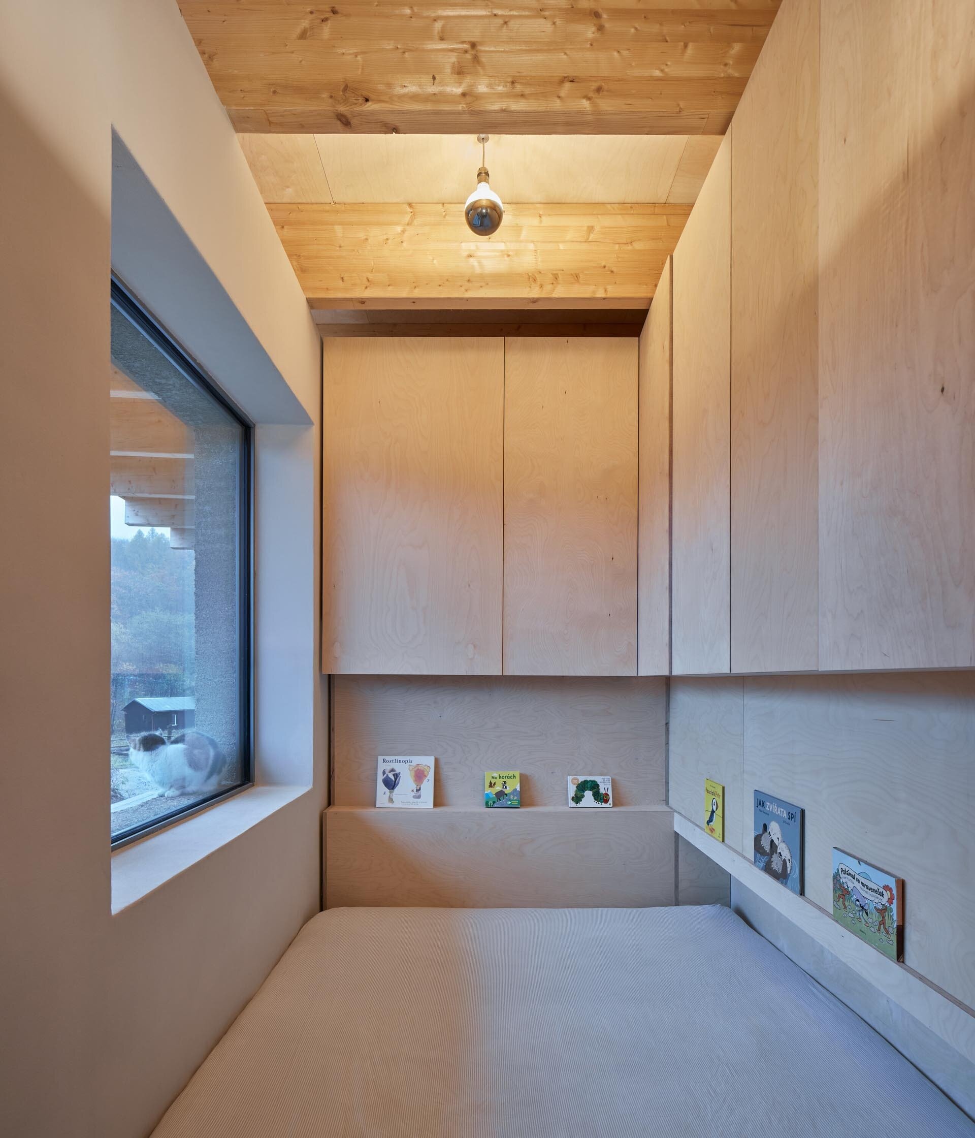 A simple children’s bedroom with a built-in wooden ledge for books, keeping the space clean and functional.
