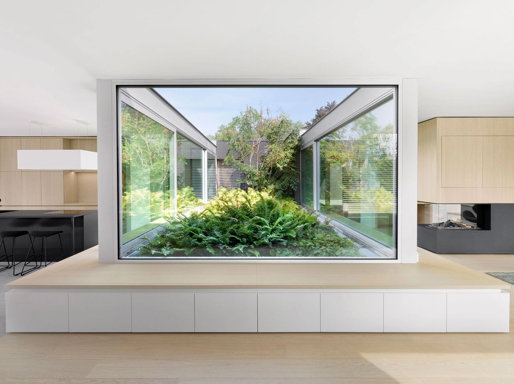 Bancos de madera empotrados rodean los grandes ventanales, creando un lugar tranquilo para disfrutar de las vistas al jardín.