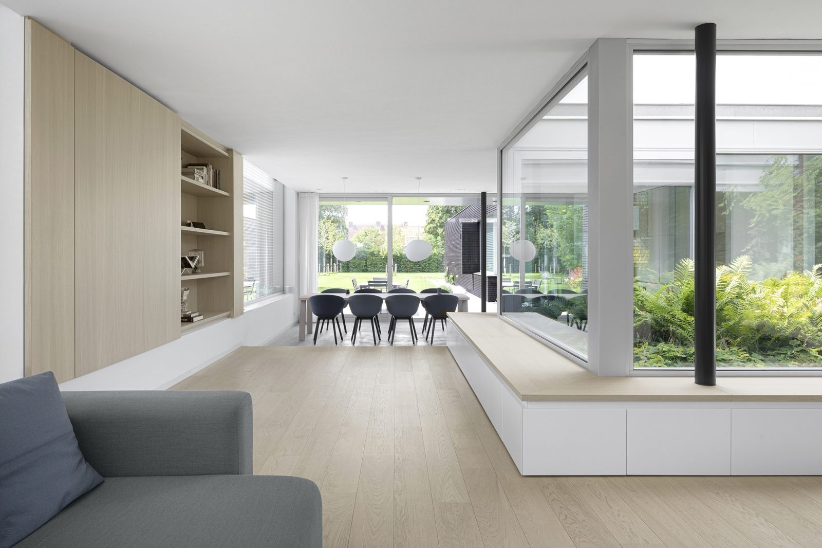 Bancos de madera empotrados rodean los grandes ventanales, creando un lugar tranquilo para disfrutar de las vistas al jardín.