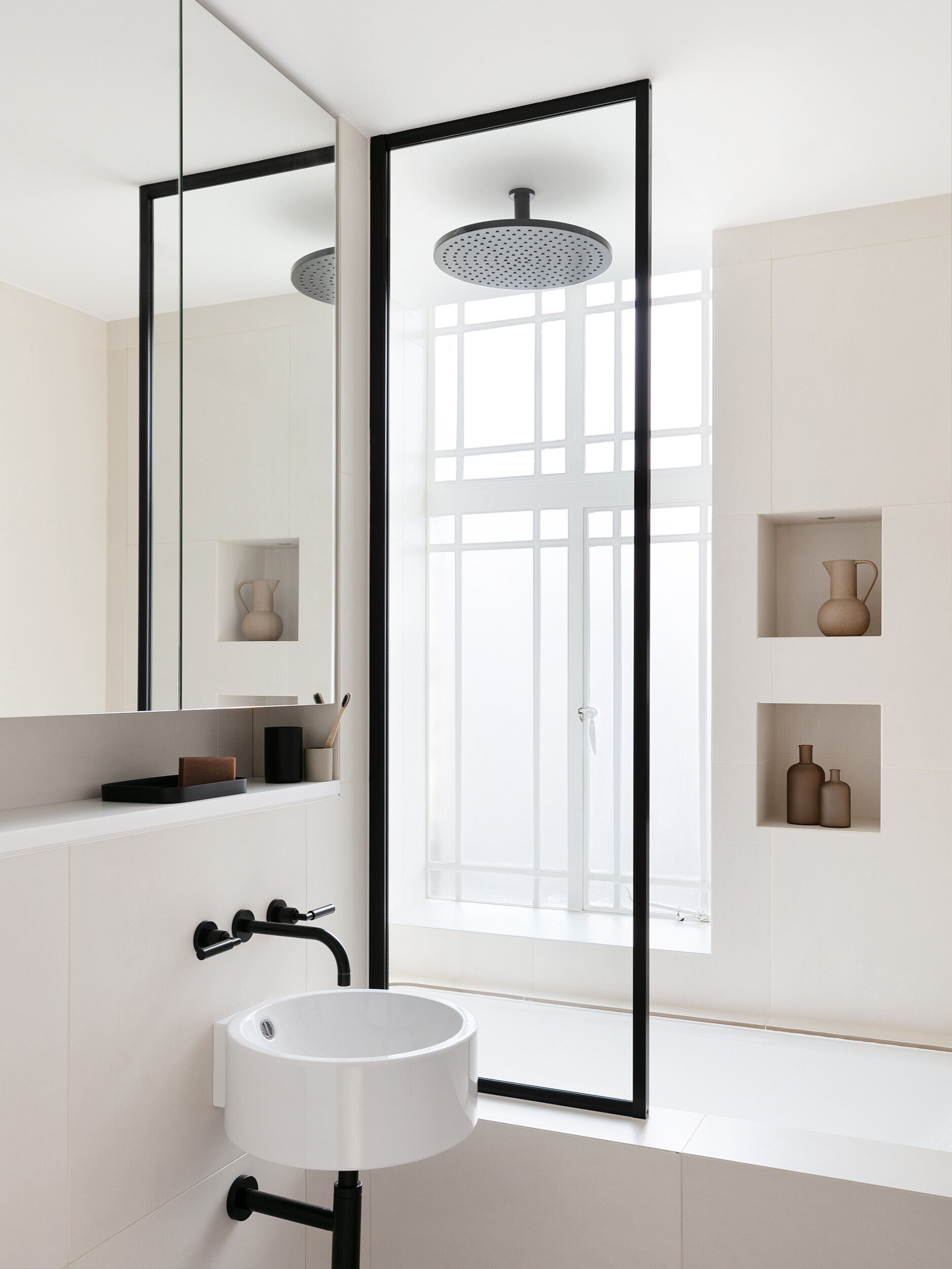 Black and white bathroom with art deco influence, hidden lighting, and spotlighted shower niches.