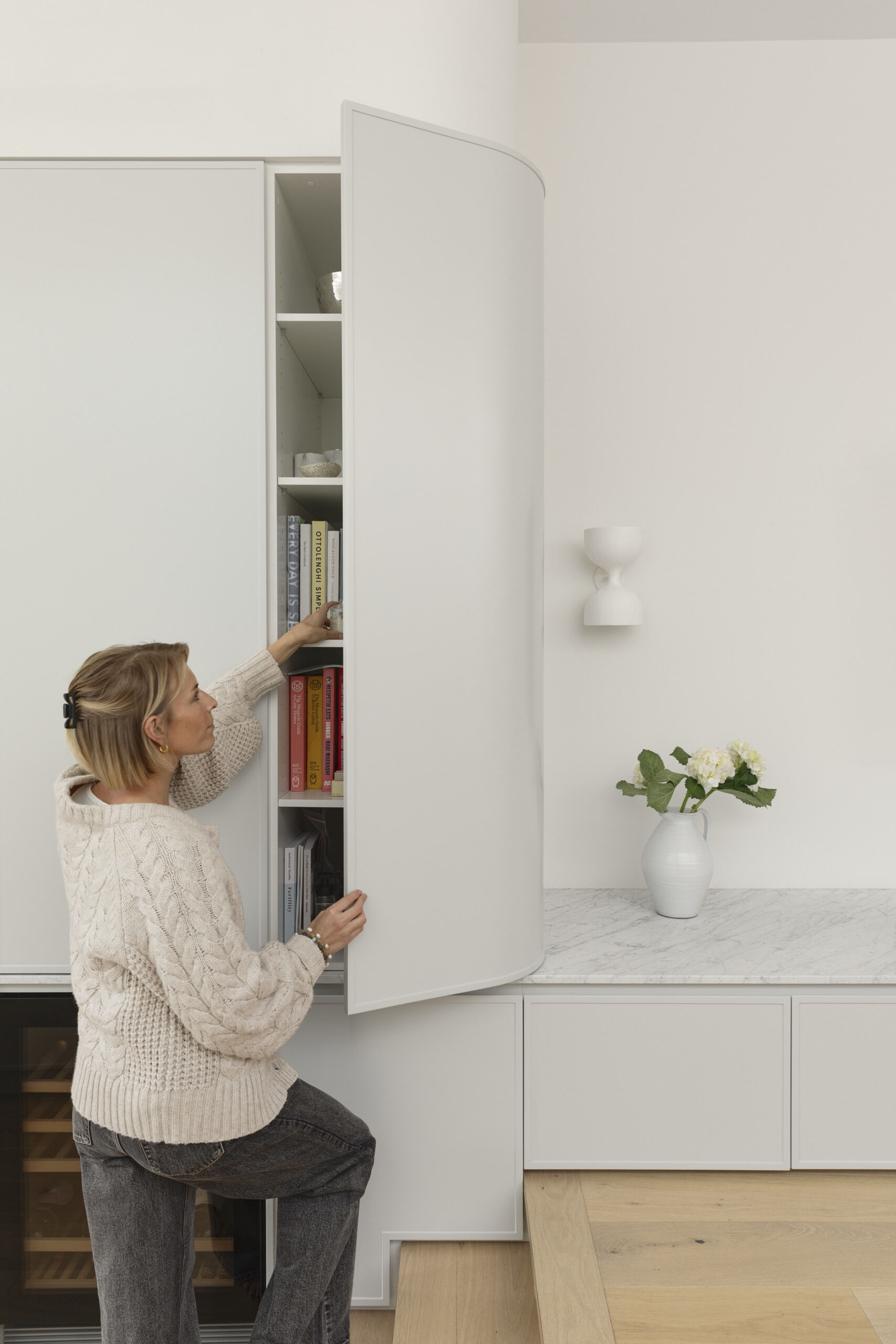 Built-in storage is integrated throughout, keeping the space uncluttered and functional. These elements blend into the architecture, maintaining the clean aesthetic.
A subtle change in level, marked by steps, leads up into the living room, creating a gentle separation without closing off the space.