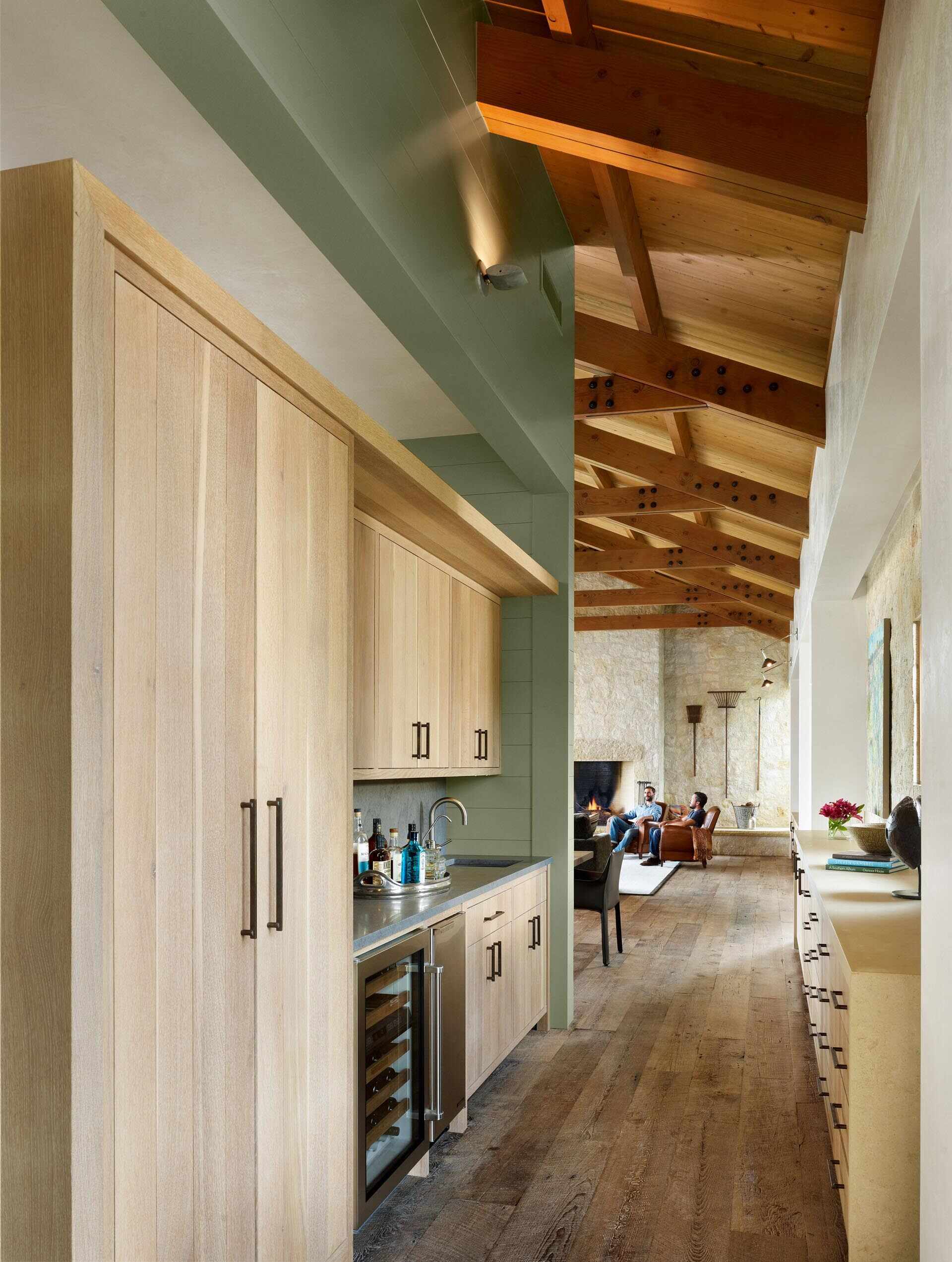 A unique kitchen designed as a wood-clad structure within the main living space, paired with a dining area and a tucked-away bar.