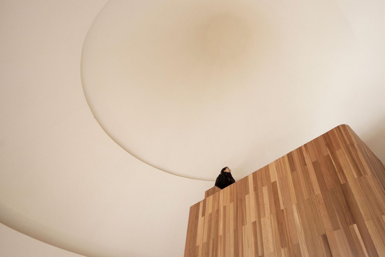 A compact loft space sits beneath the cone roof, offering a cozy spot with a unique view of the curved white ceiling.